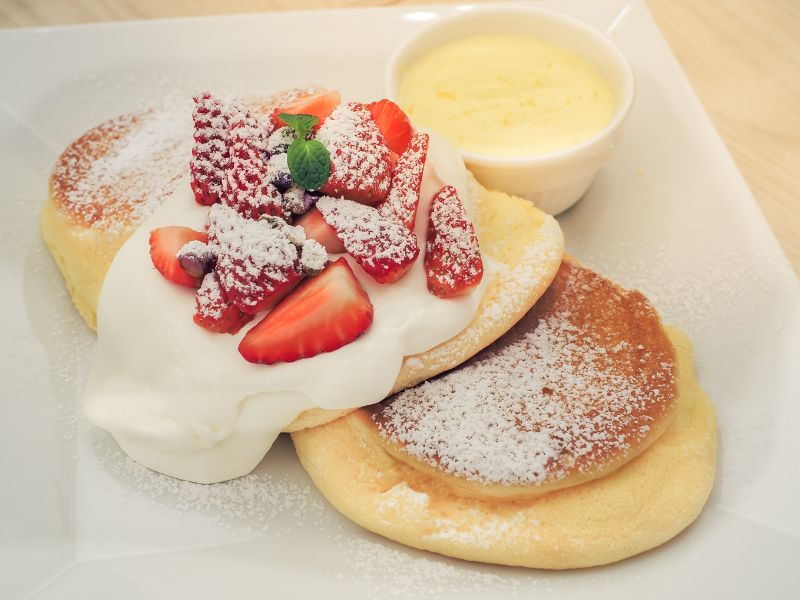 Japanese souffle pancakes with cream and strawberries on top.