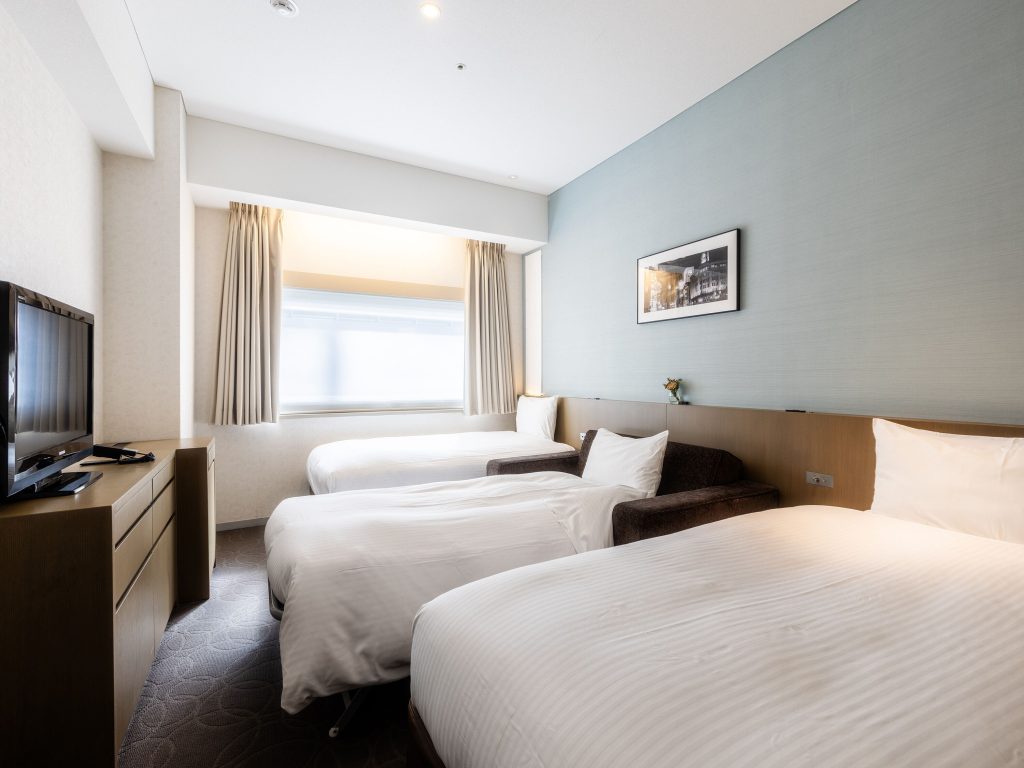 This is a hotel room of Hotel Gracery Ginza in Tokyo, Japan. There are two double beds with a TV and large window with lots of sunlight.