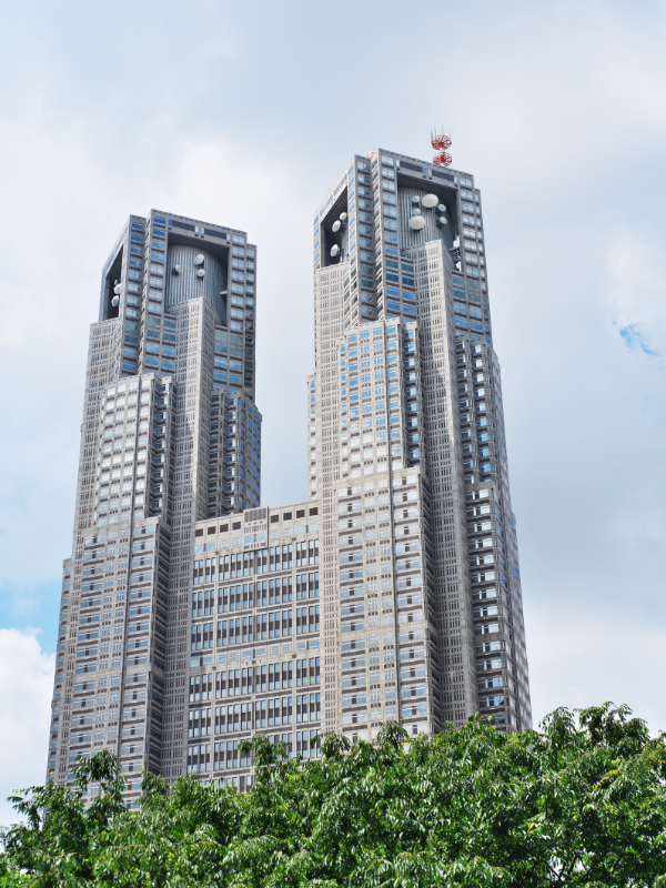 Two tall, modern towers of the Tokyo Metro building against a clear blue sky during the day.