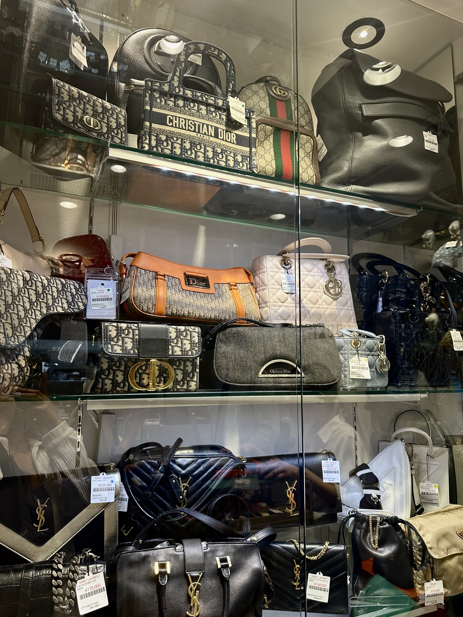Lots of different vintage pre-loved luxury handbags on display. Brands include Dior, Prada, Saint Laurent, and more.