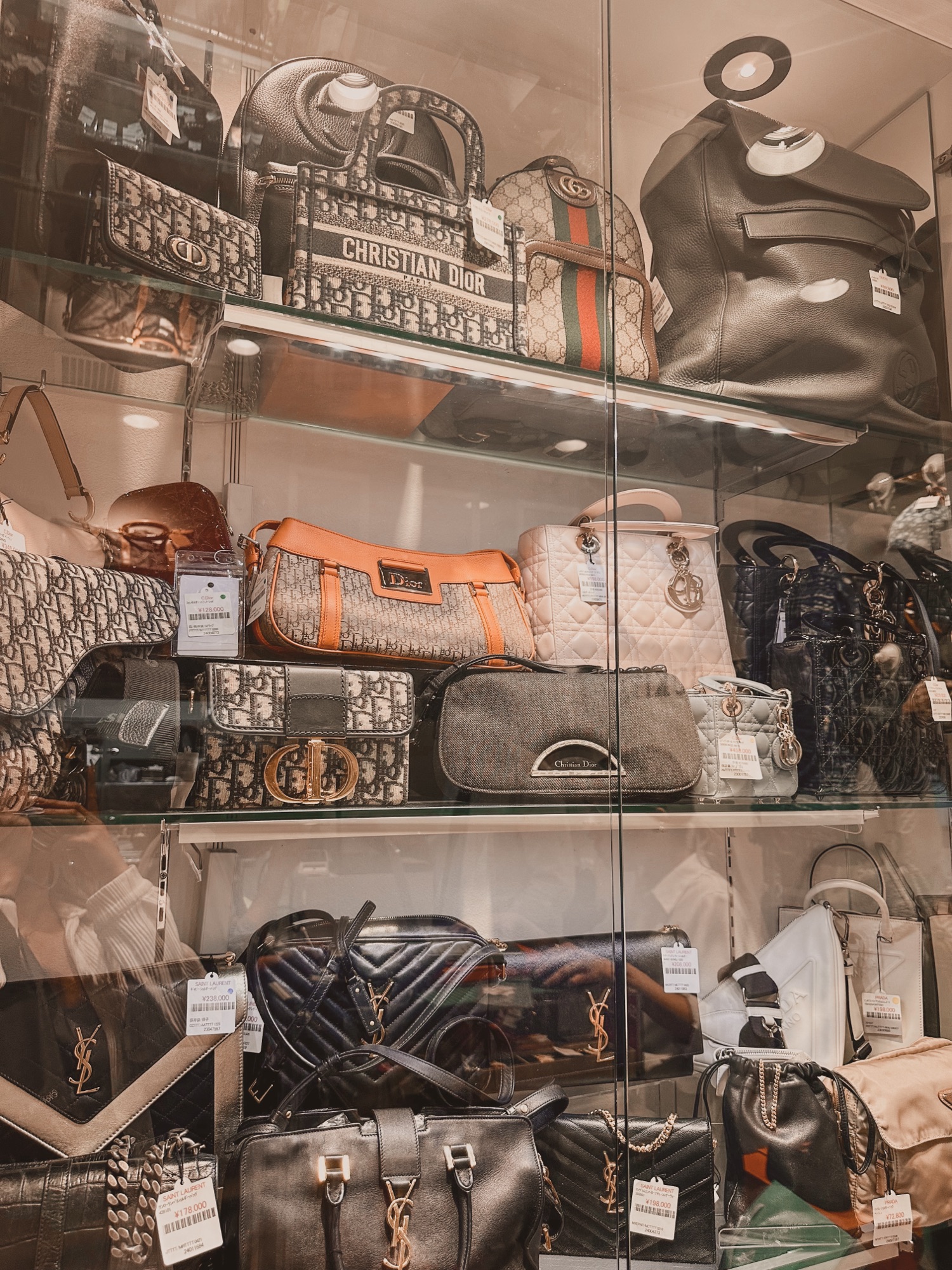 A display of pre-owned luxury bags in a thrift store in Tokyo, Japan. There are brands such as Dior, Gucci, Saint Laurent, and more.