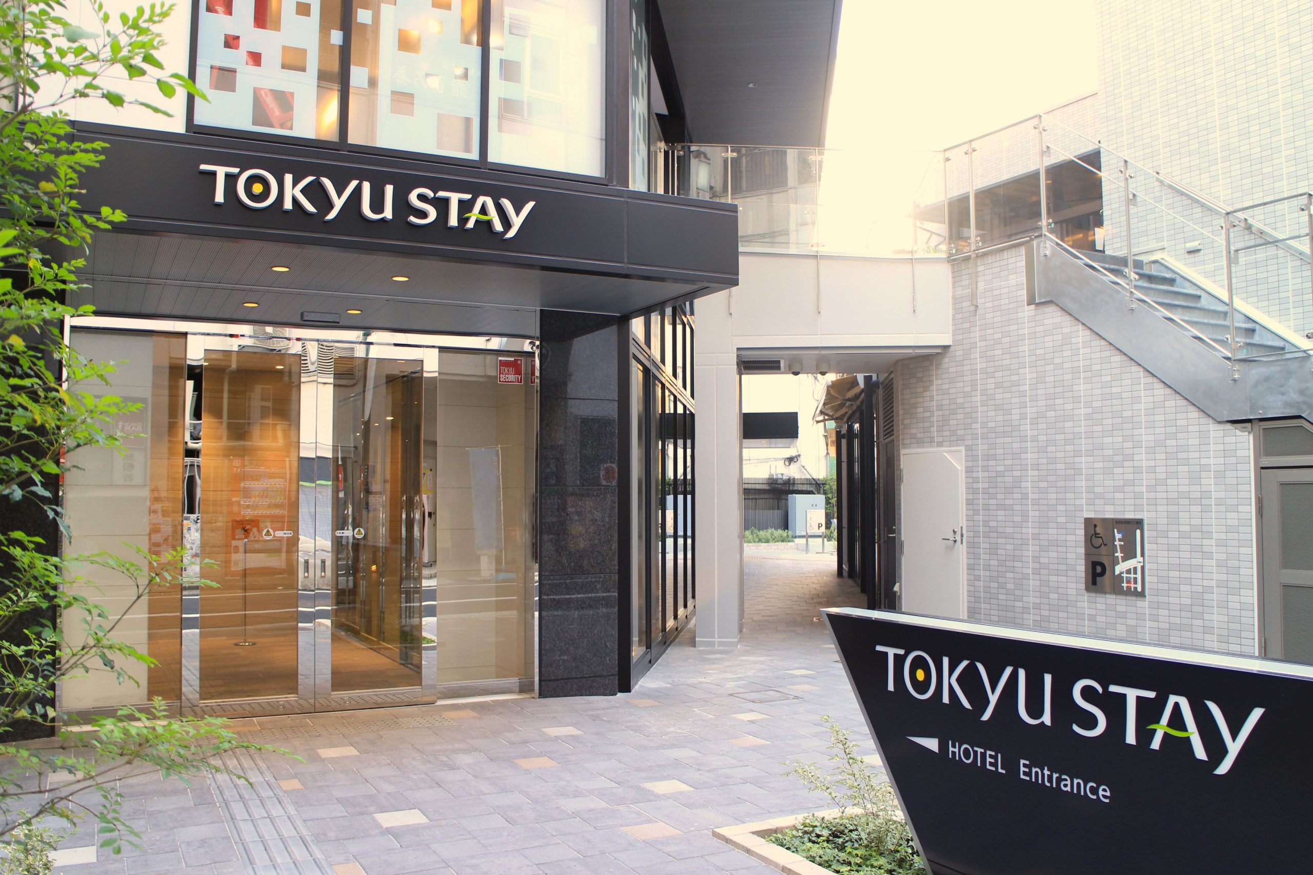 The exterior of Tokyu Stay Shinjuku, one of the best areas to stay in Tokyo for first time visitors. There are glass doors leading to the lobby, with two black signs saying Tokyu Stay. One above the hotel, one on the ground.