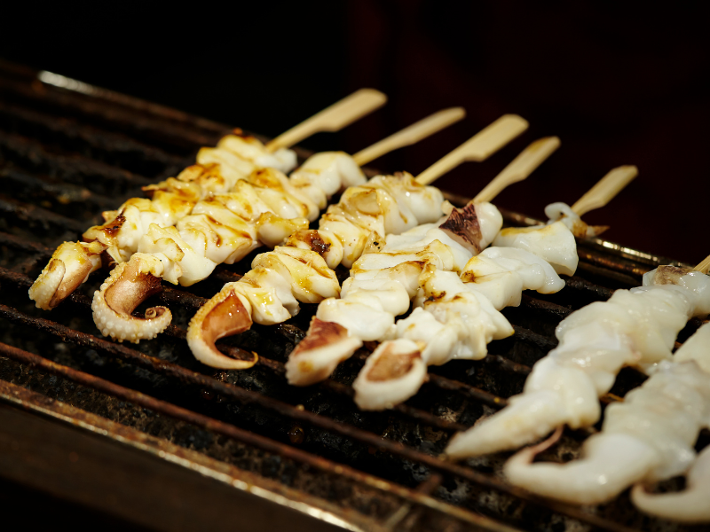 Squid seafood skewers on a grill, one of the snacks offered in Goryokaku Tower.