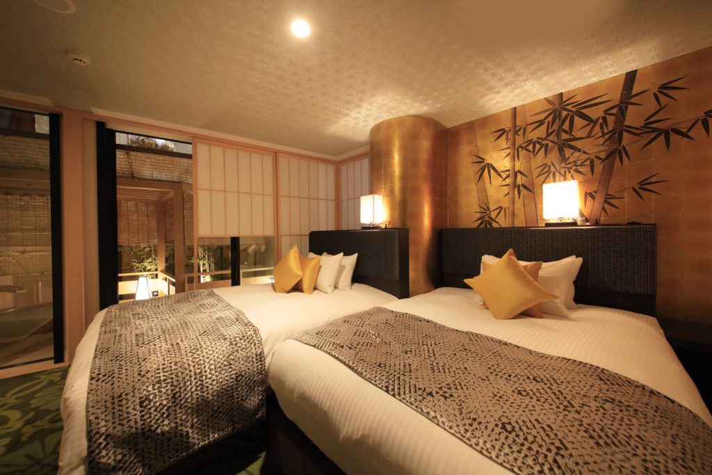 Elegant twin bedroom with gold-accented bamboo mural and sliding shoji doors opening to private bath area.