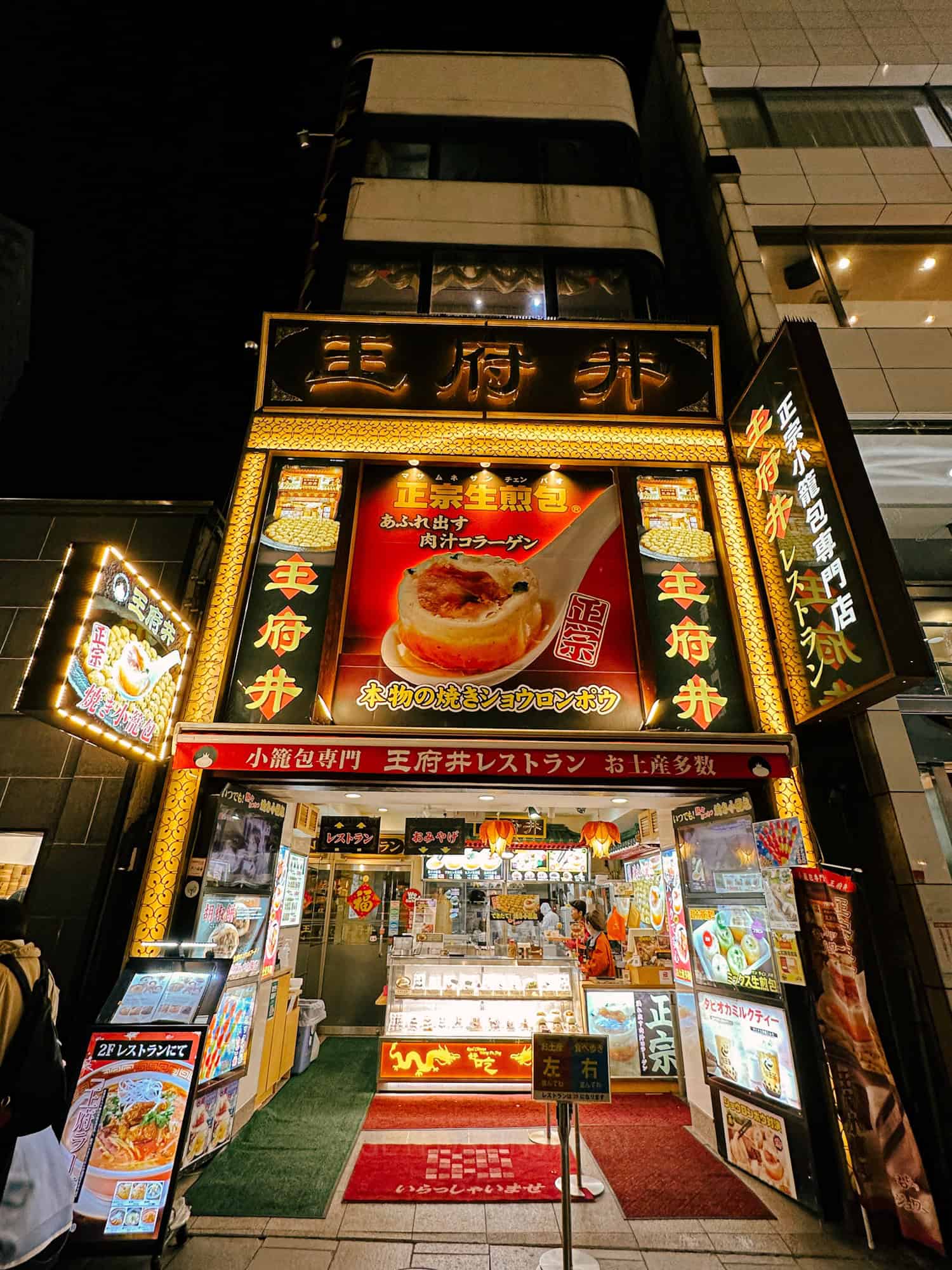 Soup filled dumplings in Yokohama's Chinatown, a quick day trip from Tokyo by train. There is a brightly lit sign with a large picture of a soup dumpling in a spoon, with Chinese characters.