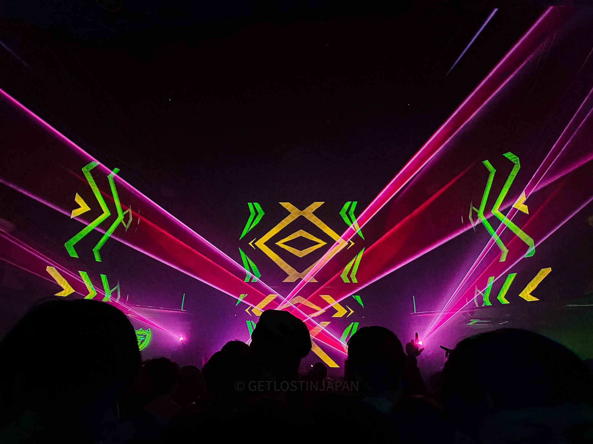 Atom nightclub in Shibuya, Tokyo. The stage has vibrant neon geometric shapes, with pink lasers facing the audience.