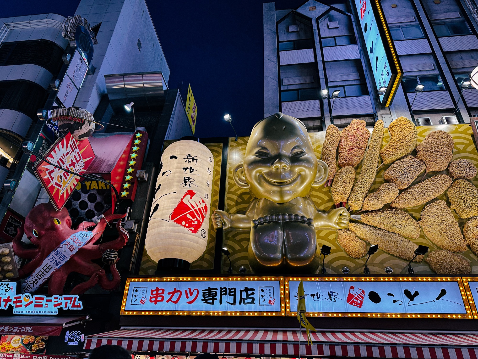 The Golden Baby sign in Dotonburi, Osaka. Next to the golden baby are various giant food signs, sincluding a red octopus.