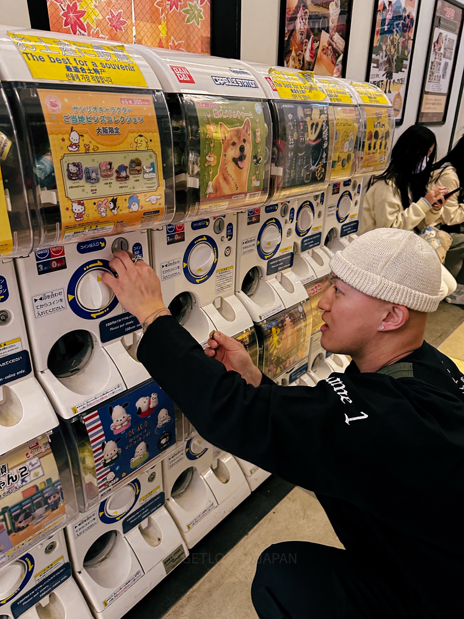 A man playing a Gachapon in Japan for a souvenir or keychain.