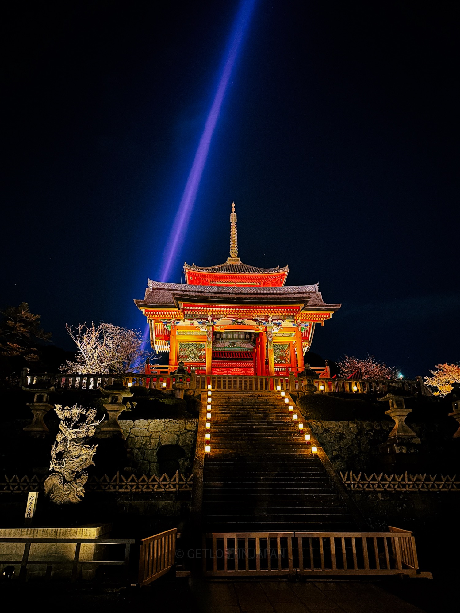 Kiyomizu-dera temple during a special night viewing. The red temple is brightly illuminated and looks especially colorful as one ascends the lit staircase.