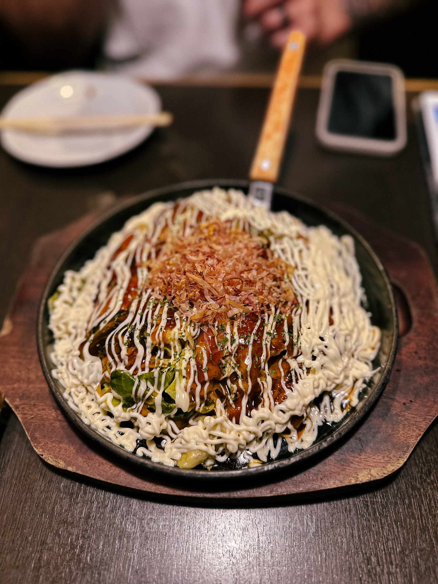Okonomiyaki, a popular dish from Osaka made from consisting of wheat flour batter. The dish is topped with white sauce, cabbage, and bonito flakes.