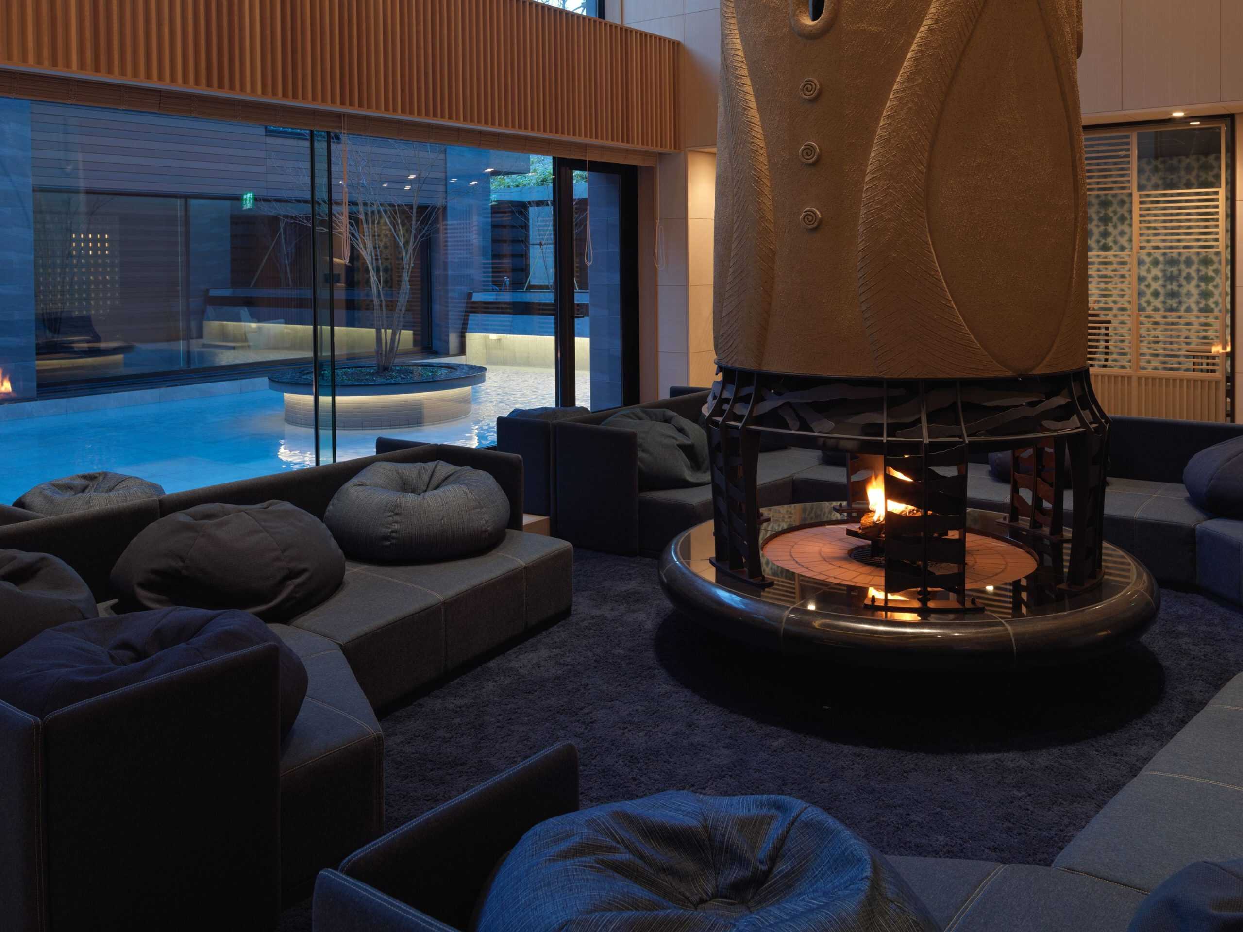Stylish indoor lounge at Lake Shikotsu Tsuruga Besso Ao no Za, featuring a central fireplace and tranquil pool, designed for ultimate relaxation in one of Sapporo’s premier 5 star hotels.