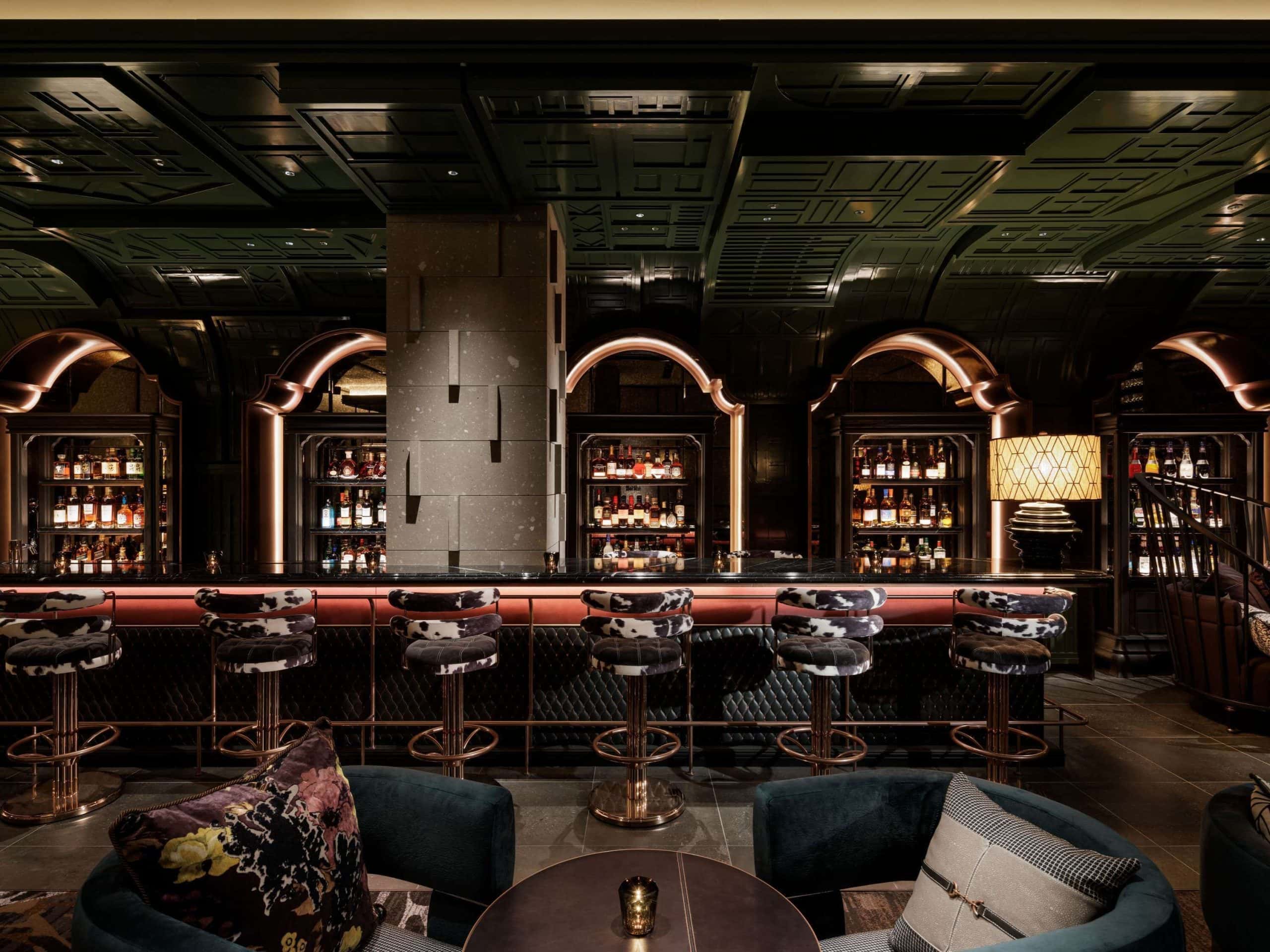 The glamorous bar at Hotel Sosei Sapporo – MGallery Collection, featuring rich green ceilings, velvet stools, and a wall of curated spirits.