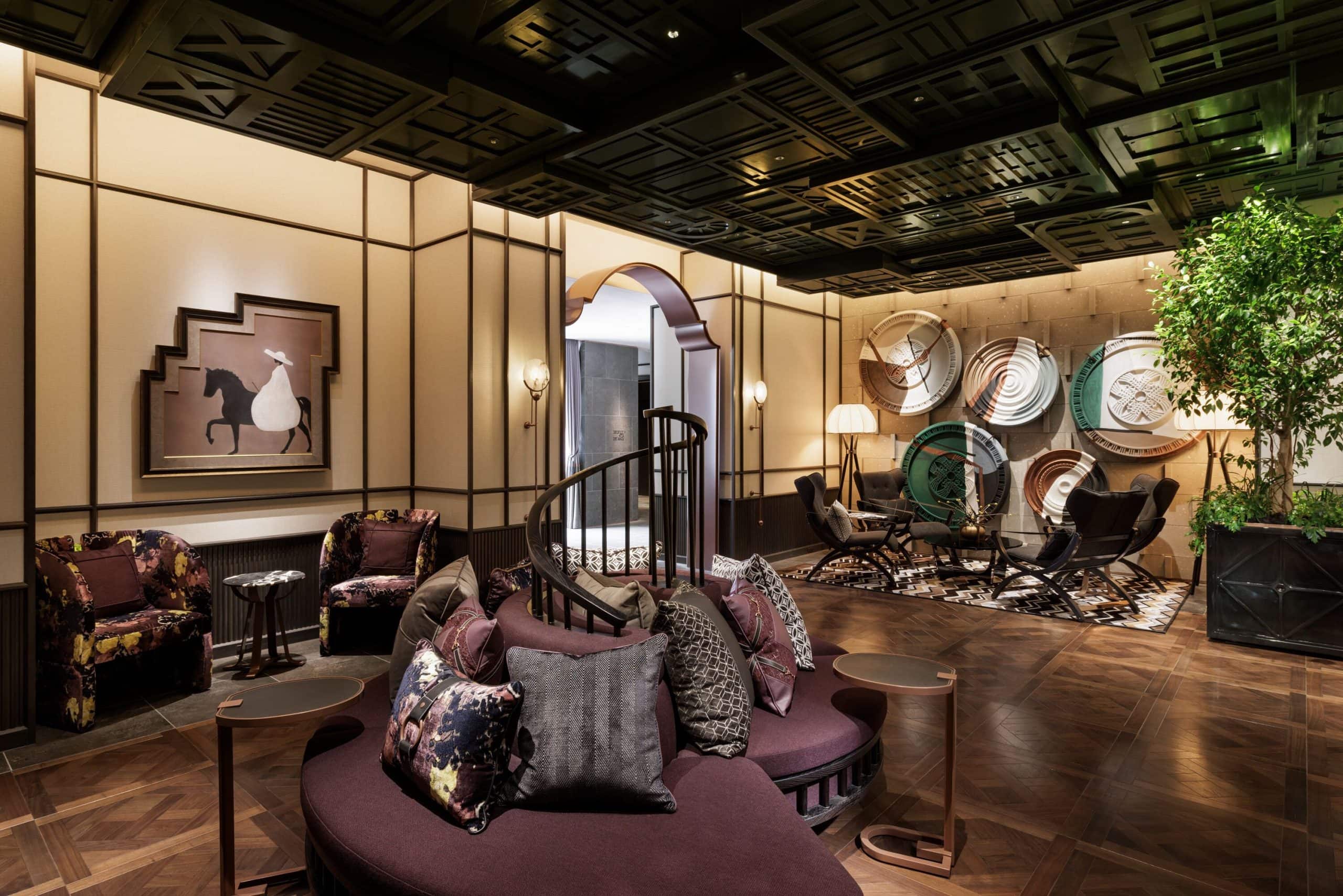 The stylish lounge at Hotel Sosei Sapporo – MGallery Collection, blending dark wood, sculptural wall art, and plush seating under a statement ceiling.