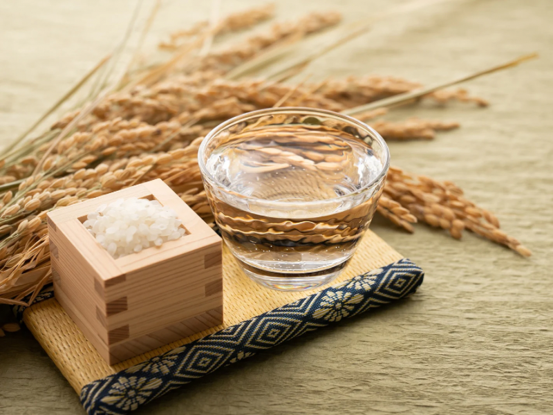 A traditional glass of sake with rice grains in a masu box—hot sake, or atsukan, is a classic way to warm up in Sapporo’s winter.