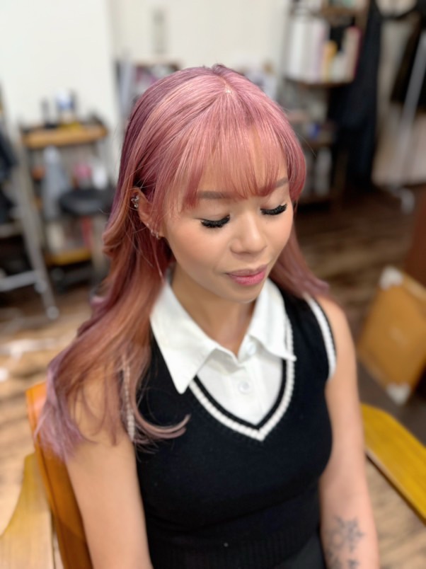 A girl with two-toned pink and red hair with her eyes closed in Number76 hair salon, an English speaking salon in Tokyo, Japan.