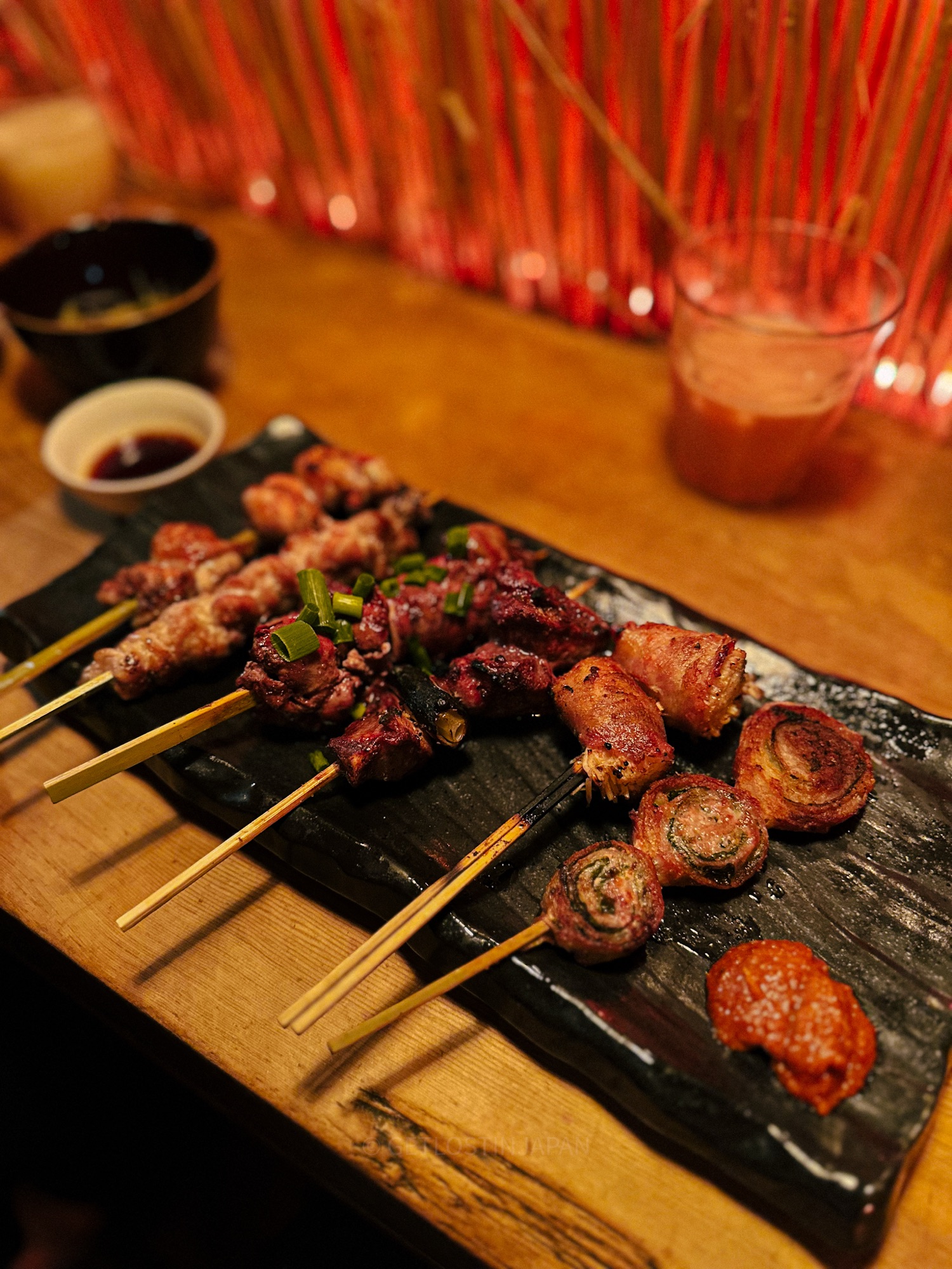 Small food skewers at an izakaya in Japan, featuring various meats and vegetables.