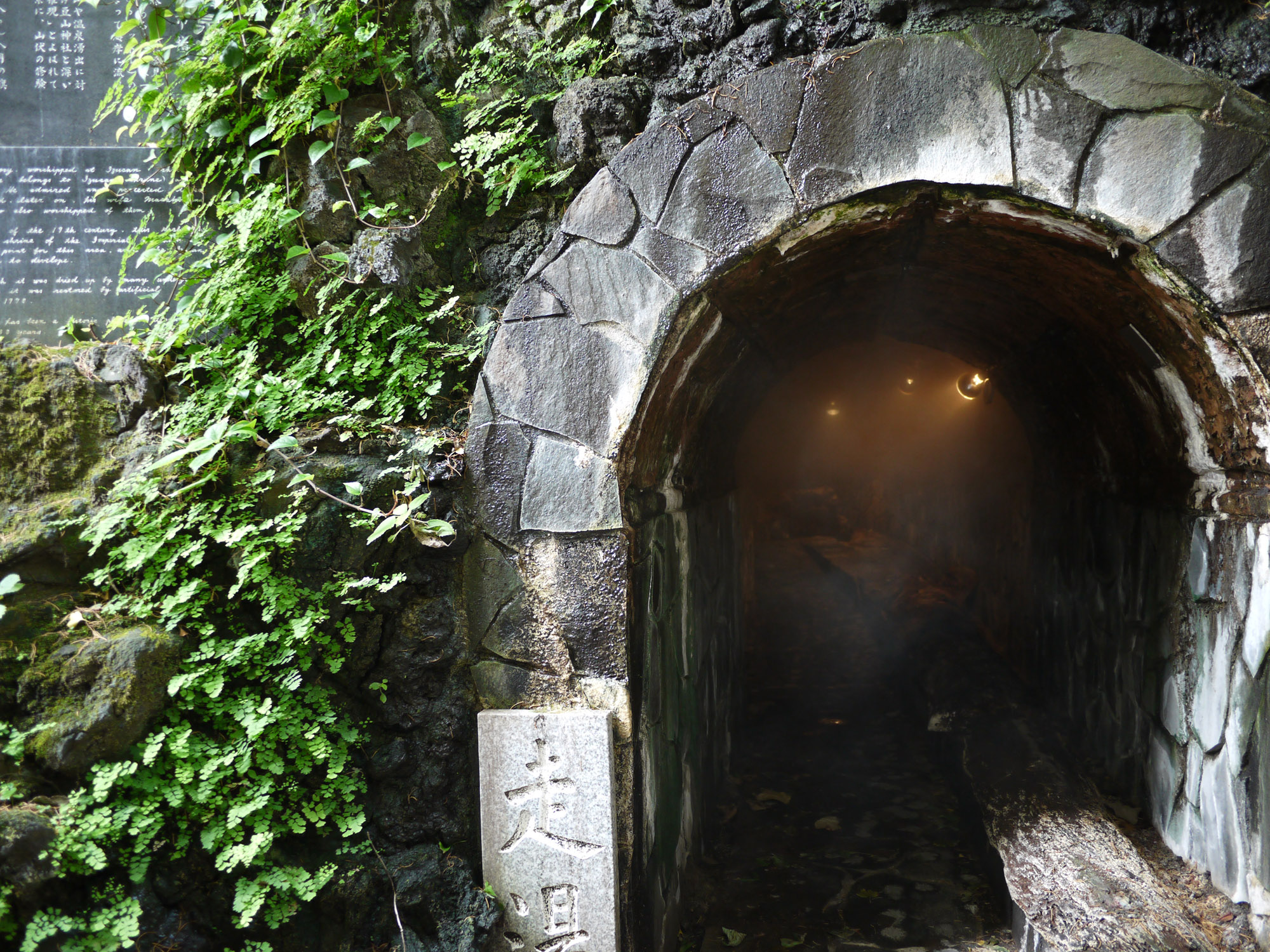 The entrance to Hashiriyu in Atami, one of the three oldest hot springs in Japan. The entrance is made of stone into a round opening, with steam visible inside.