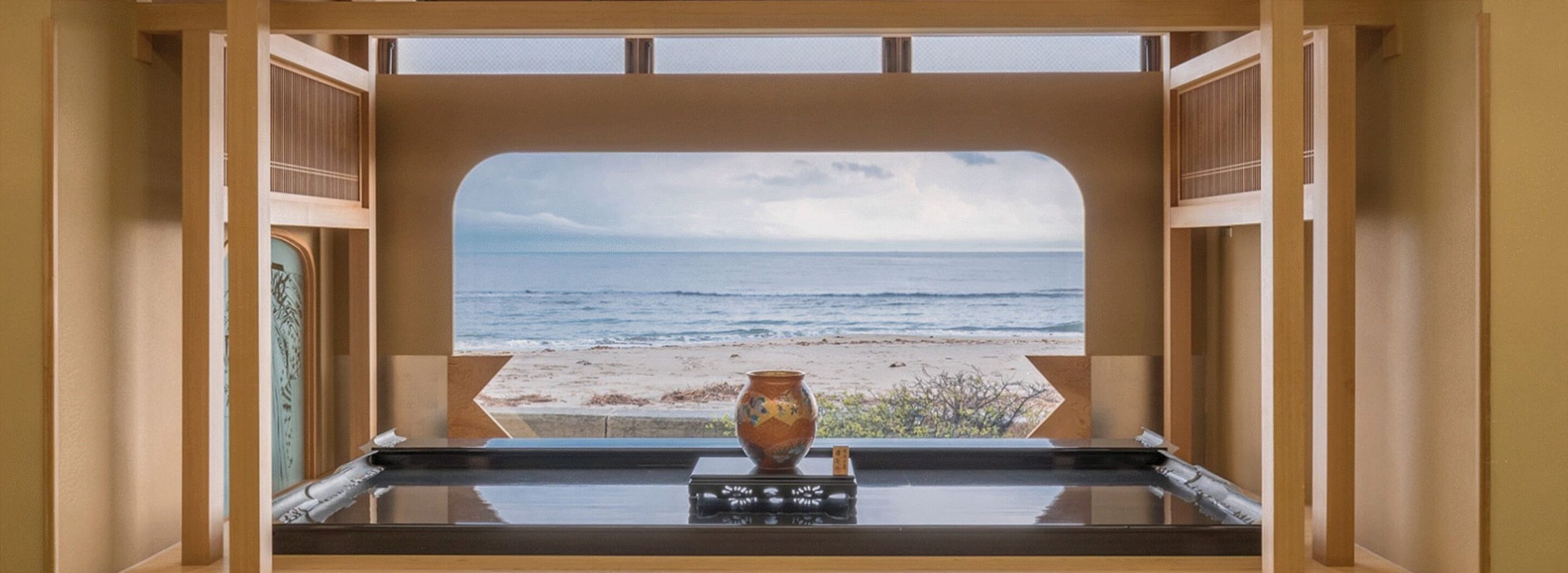 View of the peaceful sea from a guest room at Wakamatsu Kappo Ryokan with a small vase in the middle.