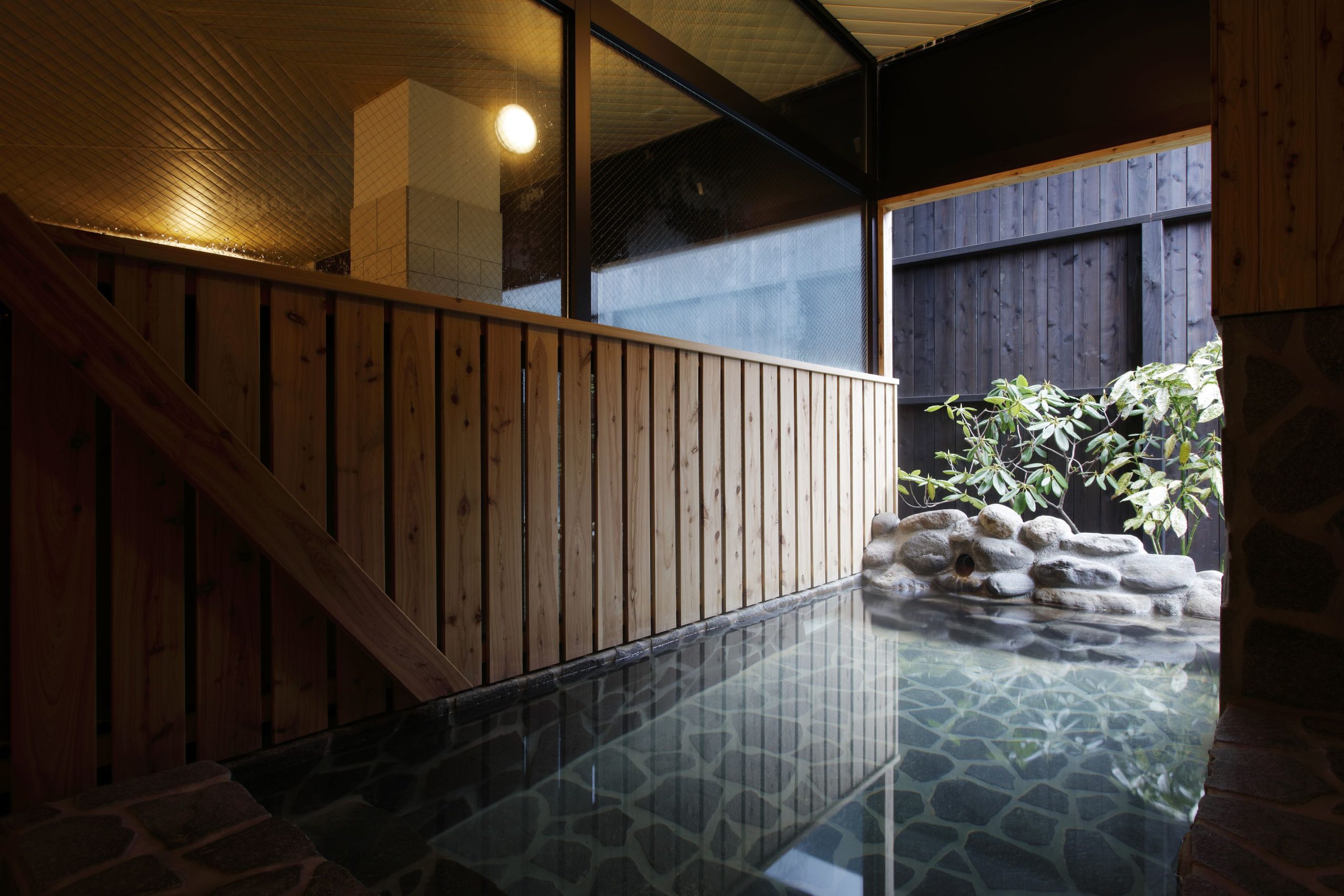 Indoor open-air onsen with stone-lined bath at Emi Hakodateya ryokan