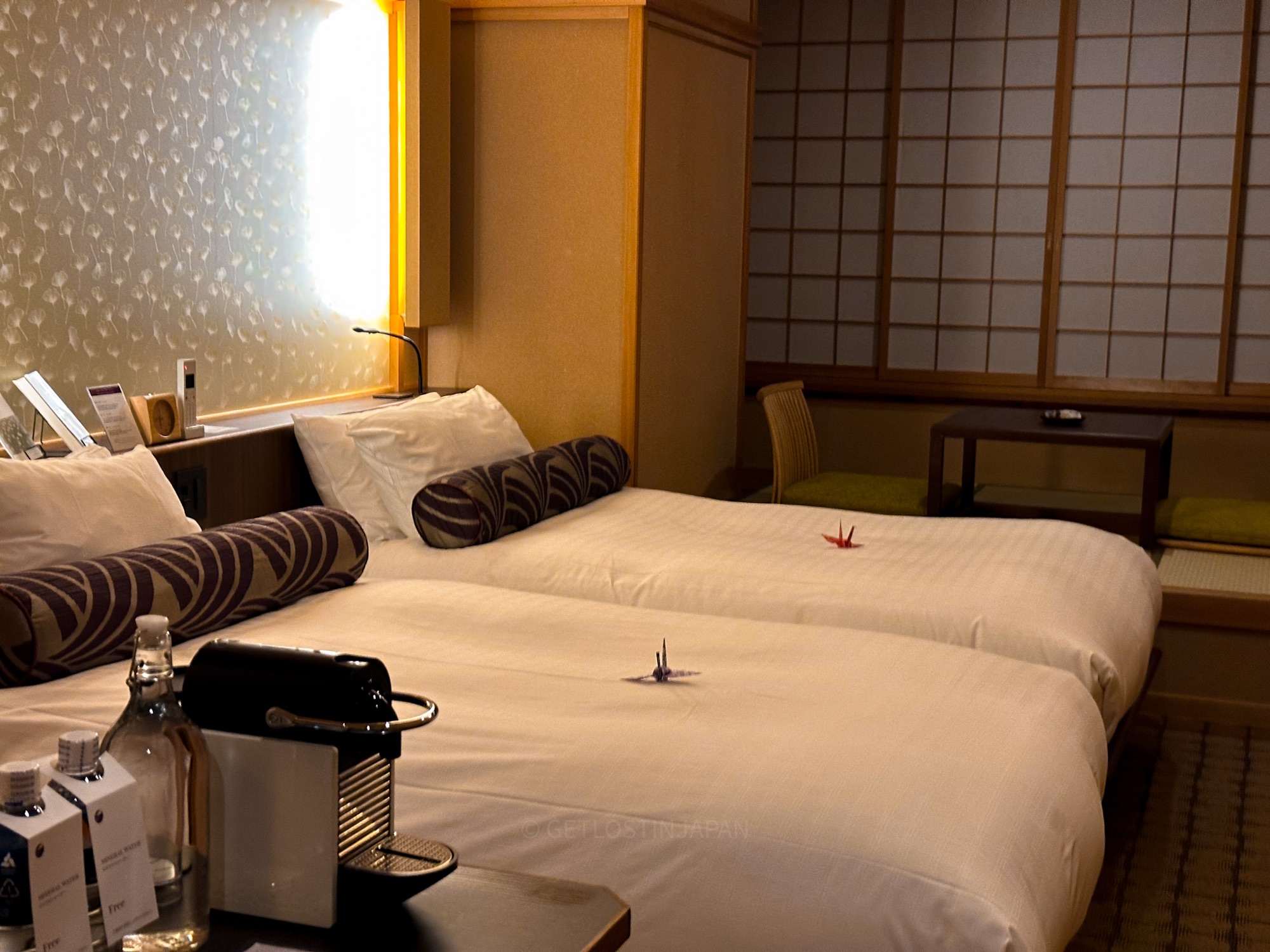 Twin beds with origami cranes and a traditional shoji window inside the Superior Twin guest room at Saka Hotel Kyoto.