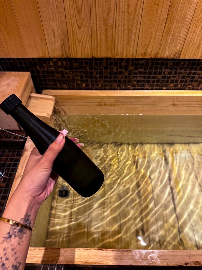 Pouring Kyoto sake into a private hinoki bath for a sake-infused soak at Saka Hotel Kyoto