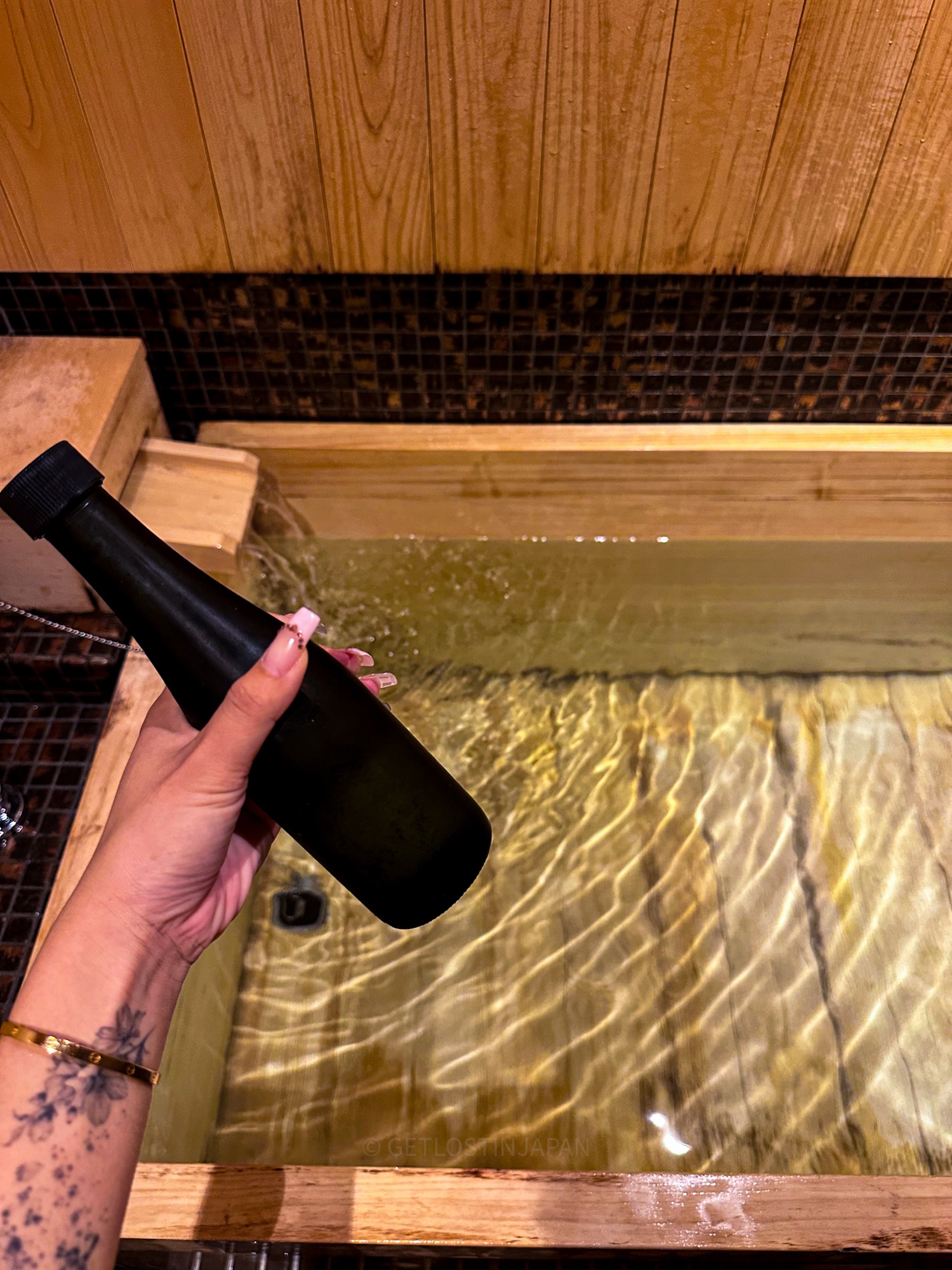 Pouring Kyoto sake into a private hinoki bath for a sake-infused soak at Saka Hotel Kyoto