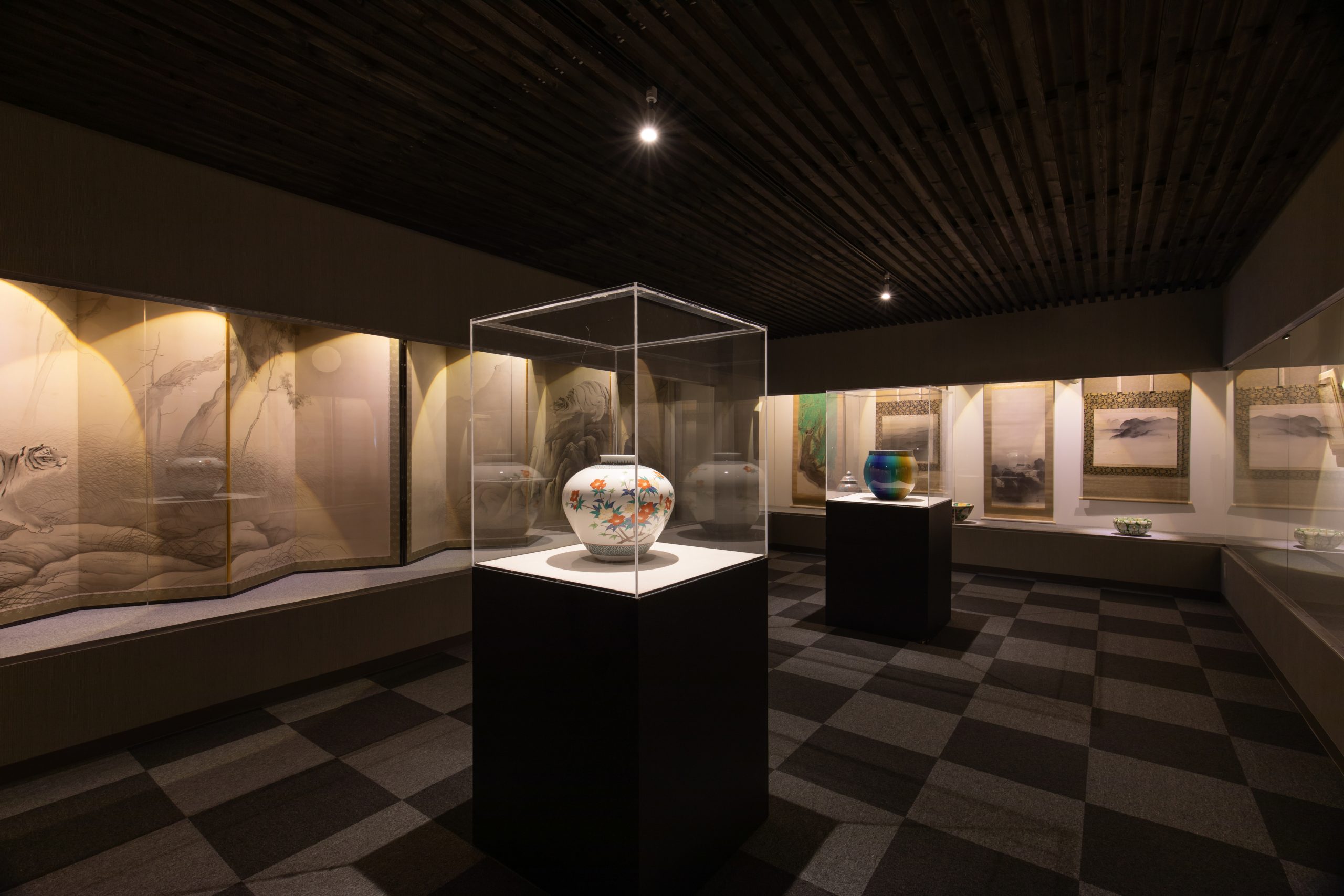 Atami Yamaguchi Museum, an art museum filled with local and international art. The room has antique vases on display in clear protective containers in a dimly lit room.