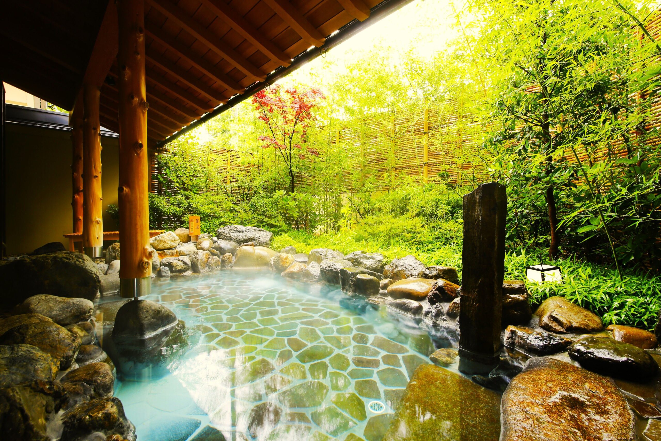 A serene open-air onsen at Arashiyama Kadensho, surrounded by bamboo and lush greenery—perfect for a relaxing stop on your Arashiyama itinerary.