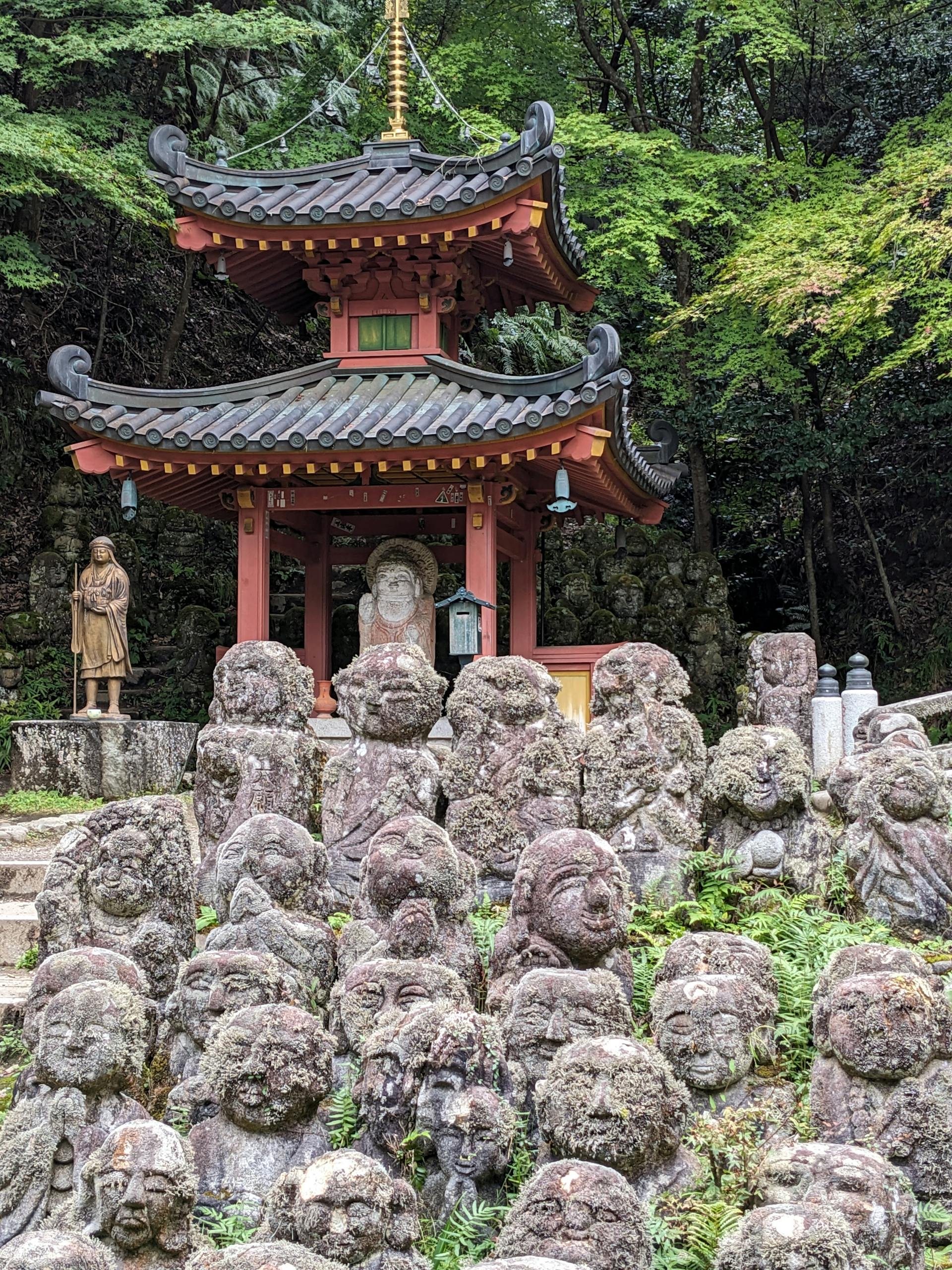 Ancient statues at Otagi Nenbutsuji Temple, Kyoto, surrounded by lush greenery.
