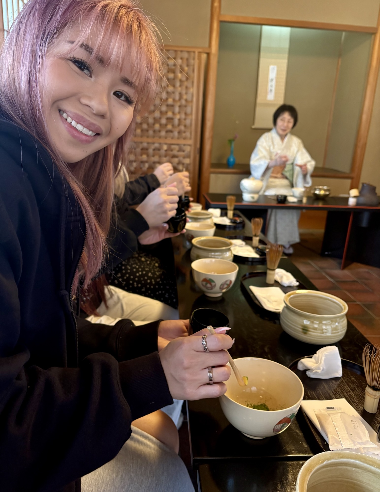 A girl participating in a traditional Japanese tea ceremony in Kyoto, learning to whisk matcha — one of the fun things to do in Kyoto for an authentic cultural experience.