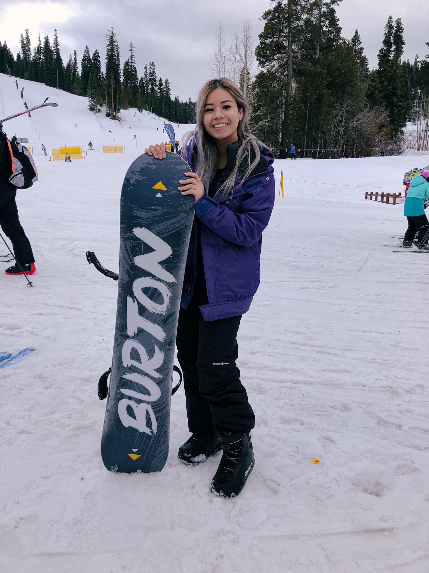 Audrey posing with her snowboard before hitting the slopes, one of the best winter things to do in Niseko.