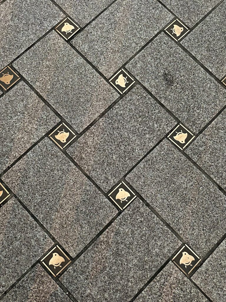 Close-up of stone pavement in Kyoto’s Pontocho district featuring small square tiles with the chidori plover bird emblem, a charming symbol inspired by the plovers found along the nearby river.