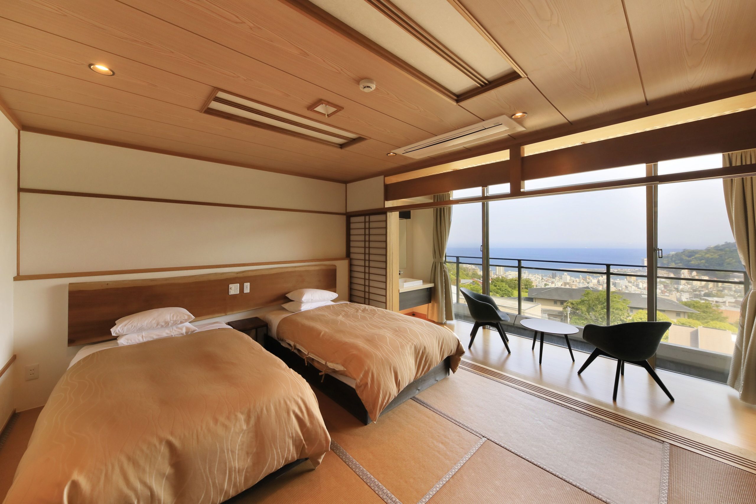 Ocean-view guest room at Atami Fuga, a stylish Atami ryokan with twin beds and tatami flooring.