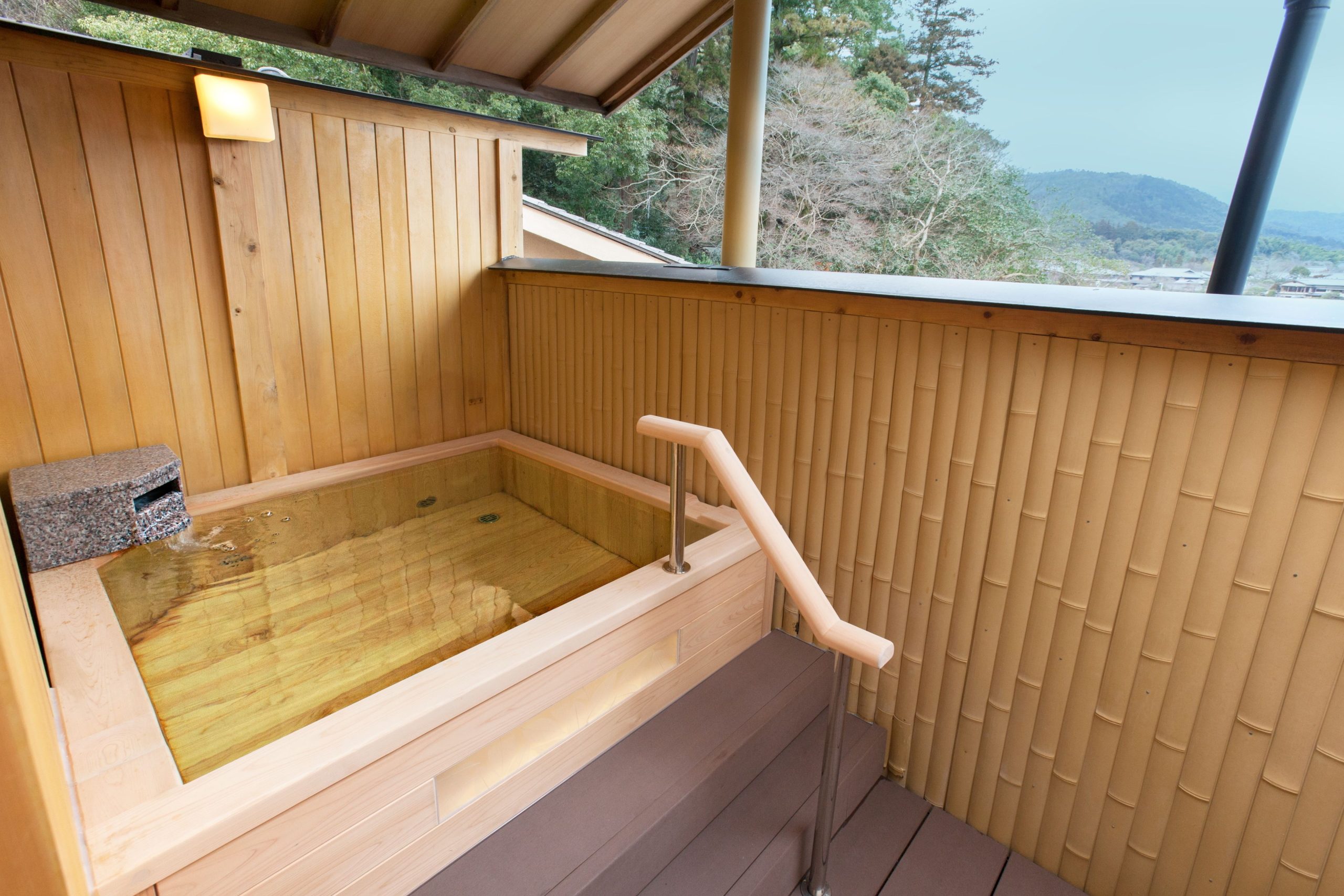 Wooden open-air bath on a terrace with mountain views at Hanaikada, offering a peaceful private soak in traditional Japanese style.