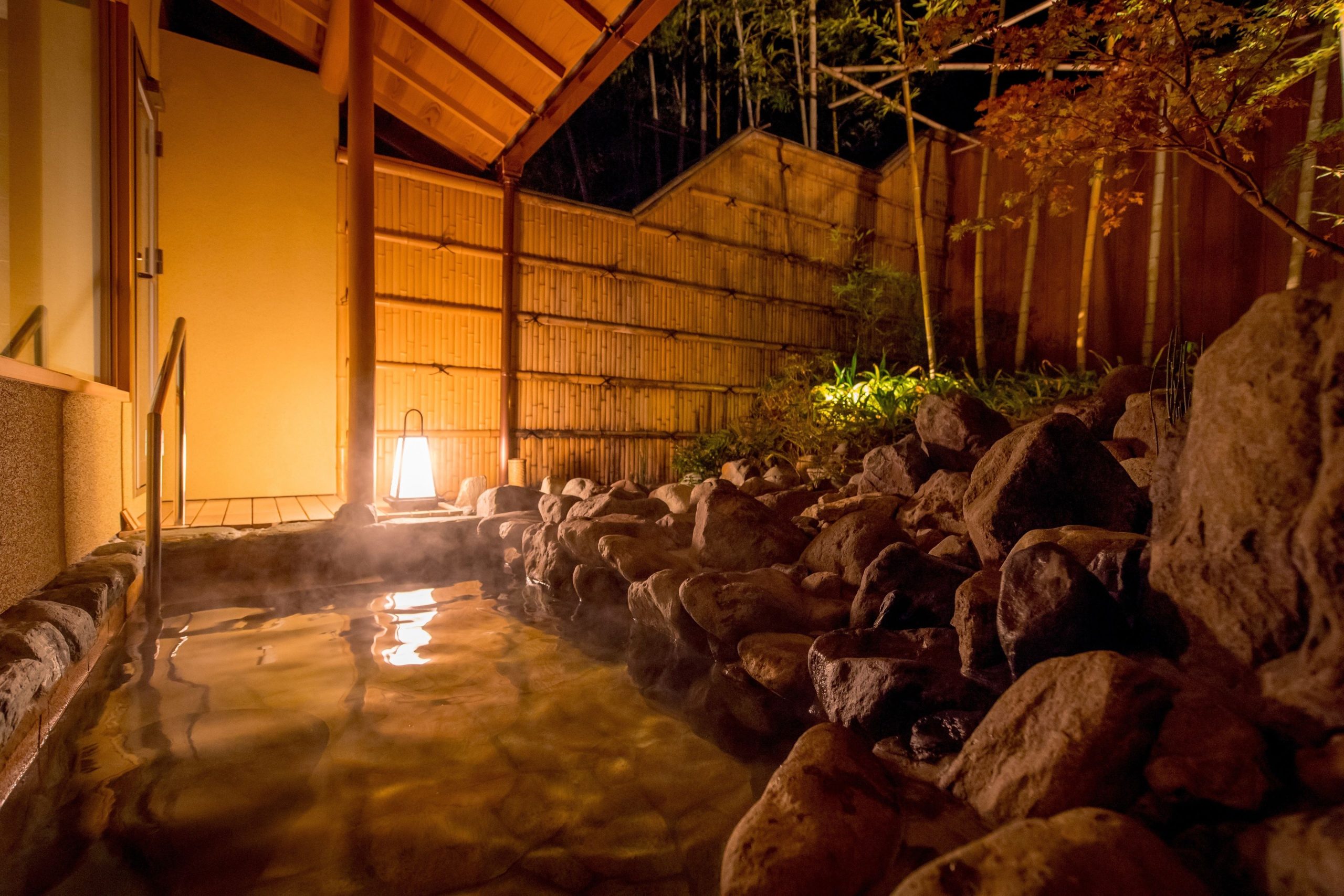 Round wooden onsen bath inside a guest suite at Suiran Hotel Kyoto, with panoramic mountain views through large windows.
