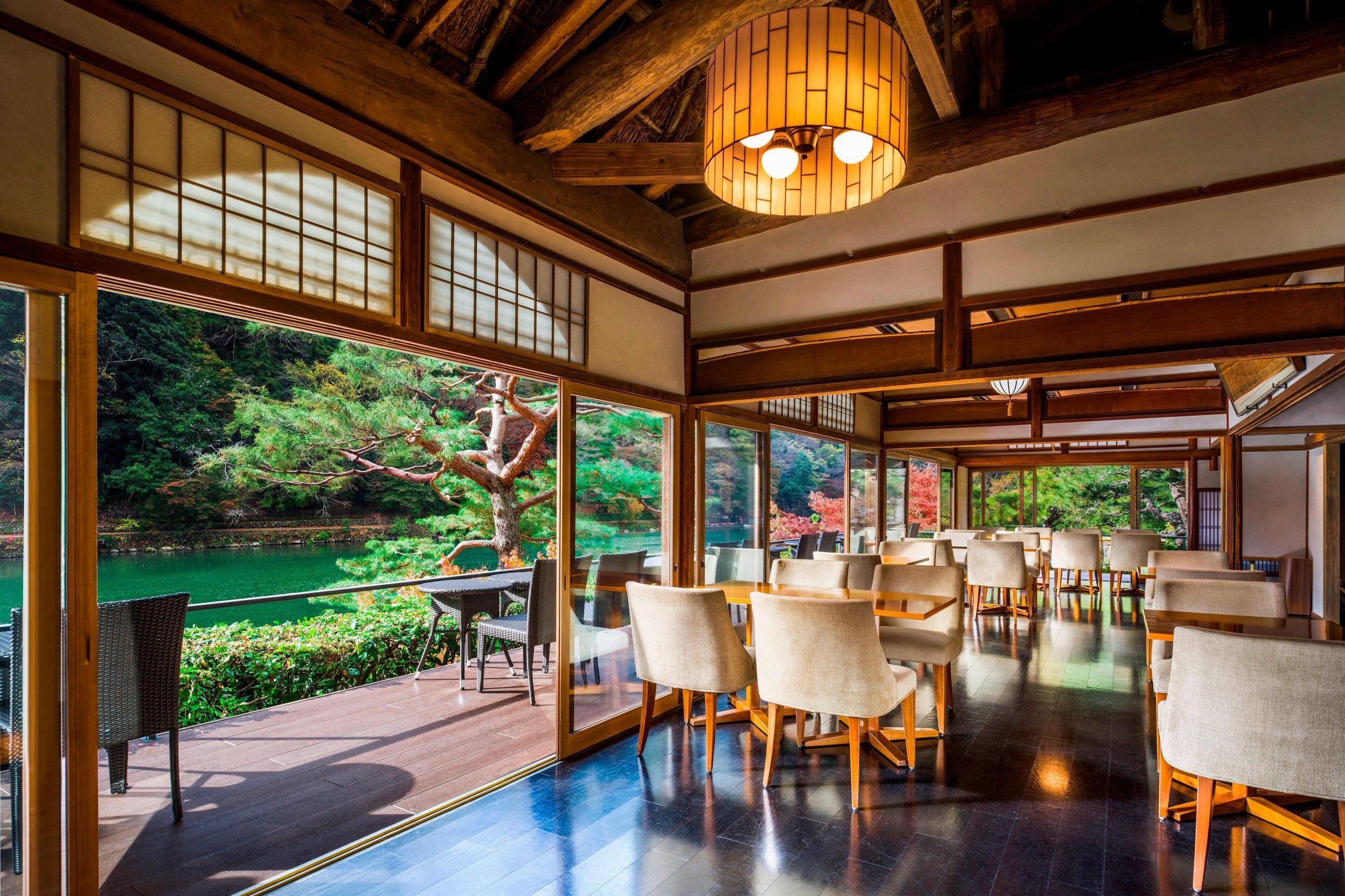 Elegant dining room at Suiran, a Luxury Collection Hotel, with wide windows facing the Katsura River and vibrant gardens of a luxury Arashiyama ryokan.