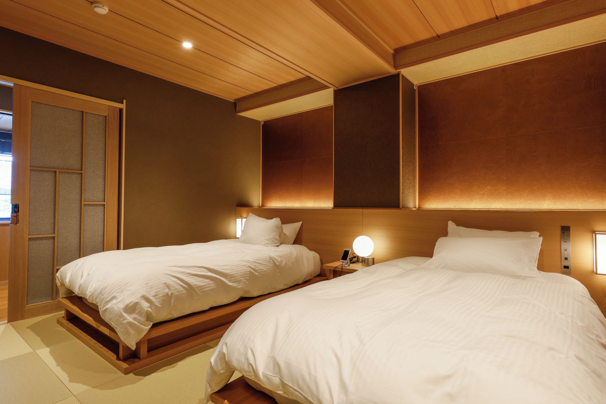 Traditional Japanese twin room at Togetsutei Ryokan, featuring tatami flooring, soft lighting, and serene minimalist design in an Arashiyama ryokan.