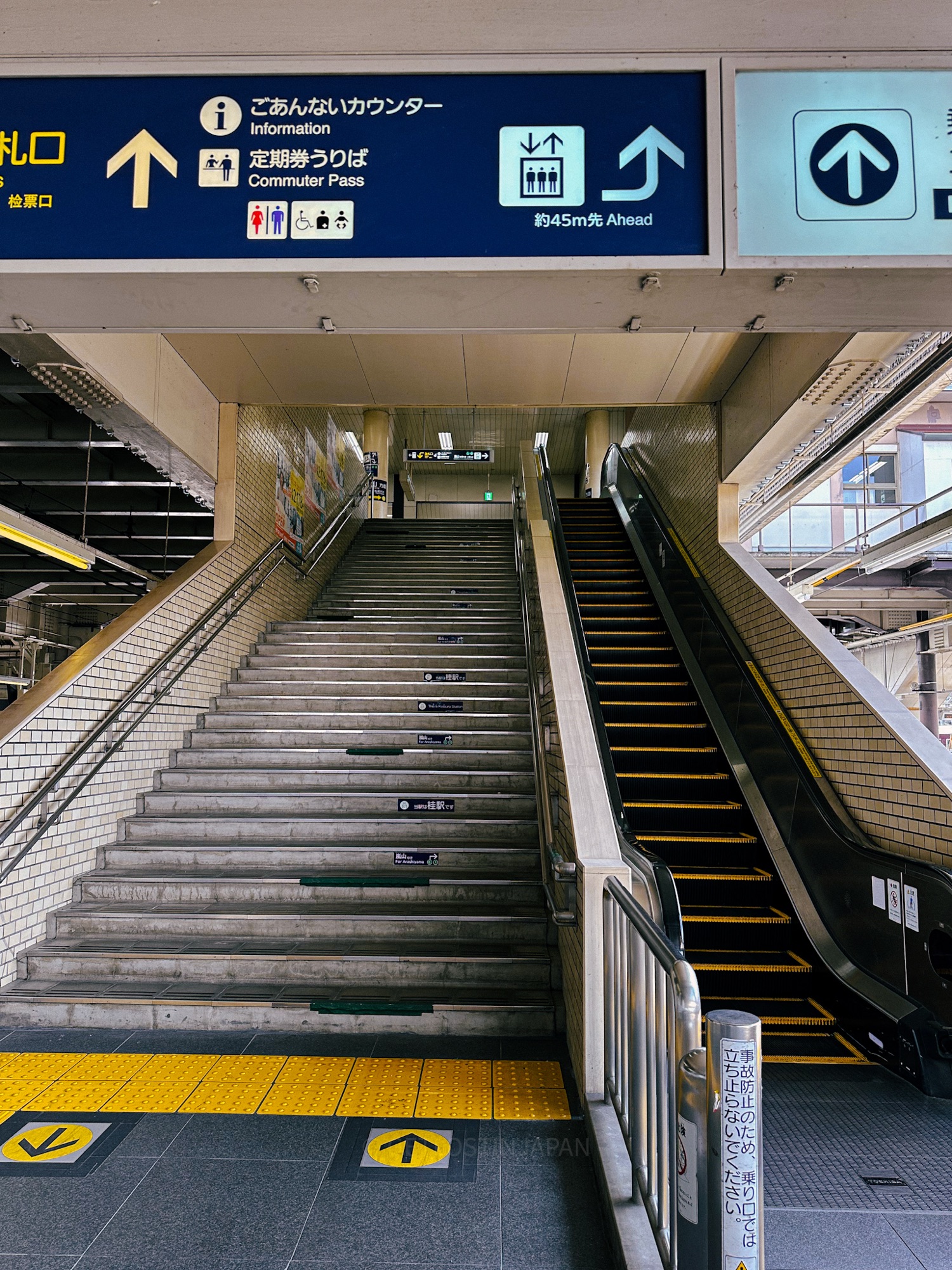 A stairway and escalator inside a Japanese train station where limited elevators make Japan luggage forwarding a convenient choice.