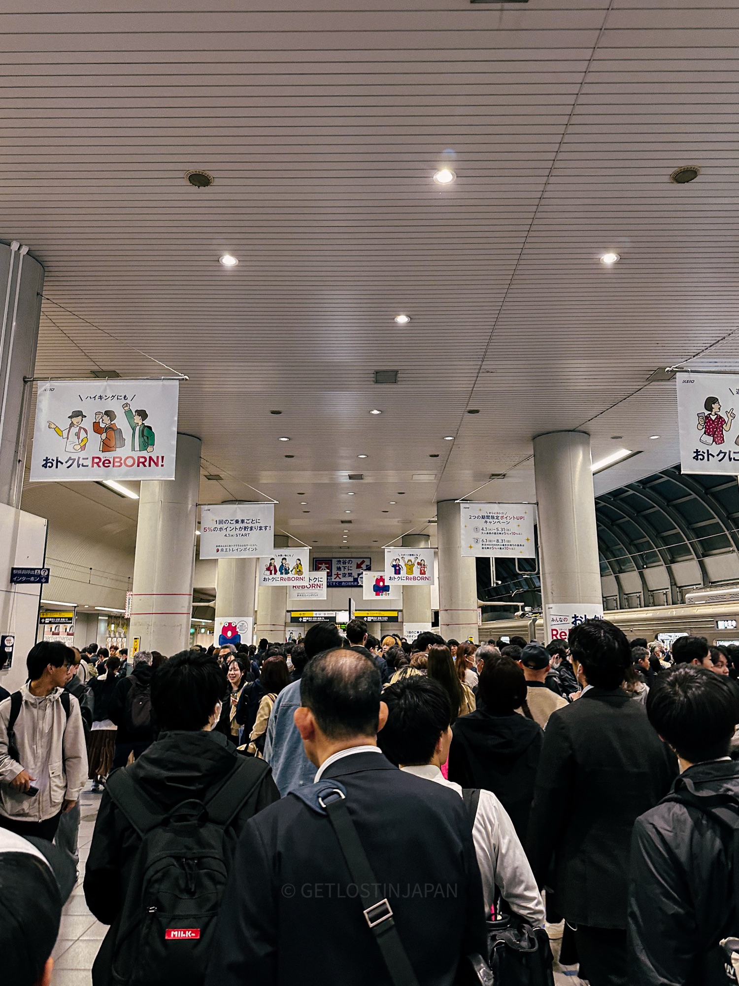 A crowded train station in Tokyo where travelers move through packed walkways, showing why moving with luggage can be challenging.