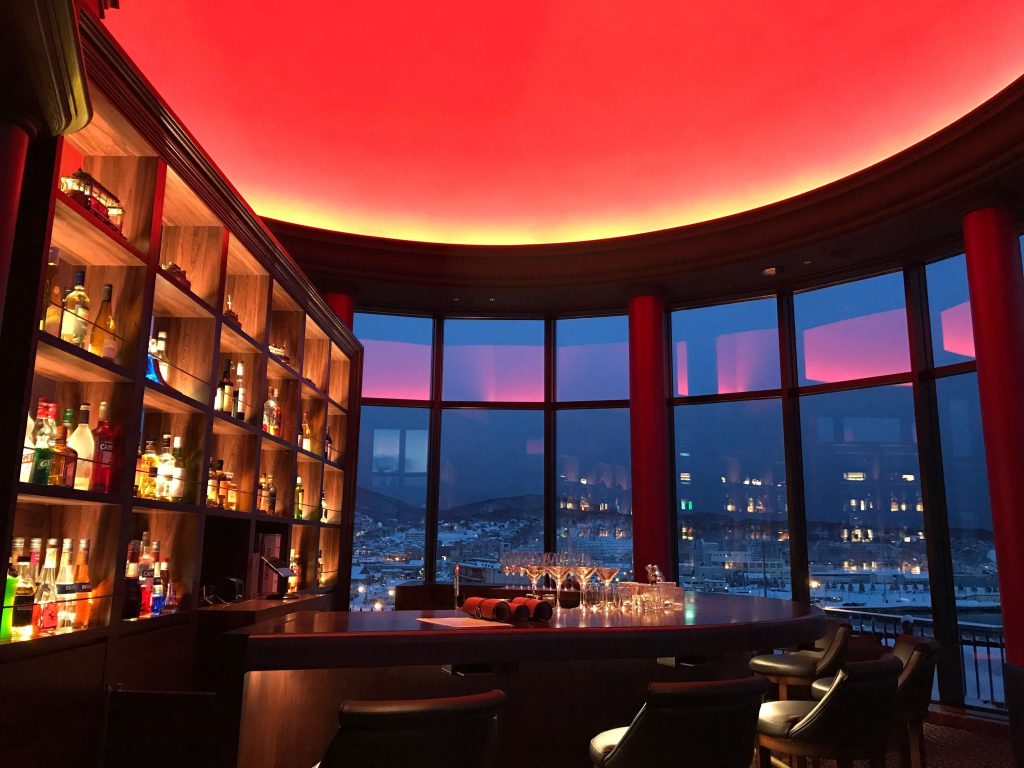 Elegant bar inside Hotel Nord Otaru overlooking the harbor at sunset, offering panoramic city views and cocktails for a memorable evening.