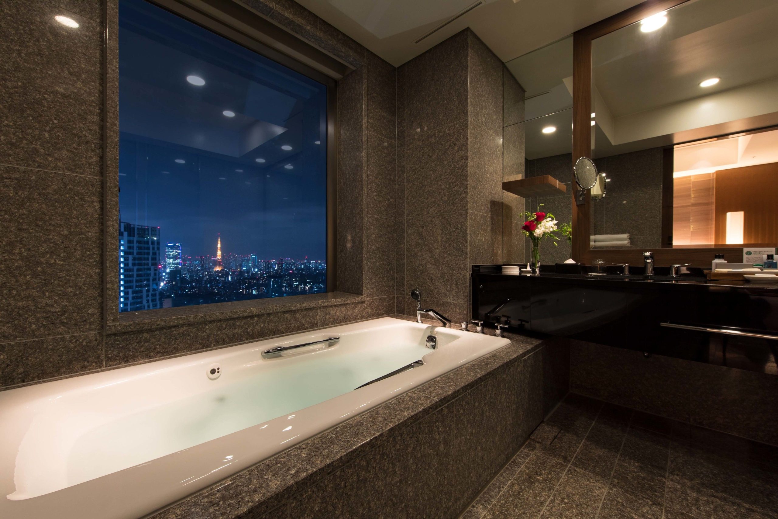 Luxurious marble bathroom at Cerulean Tower Tokyu Hotel with a soaking tub and stunning night view of Tokyo Tower.