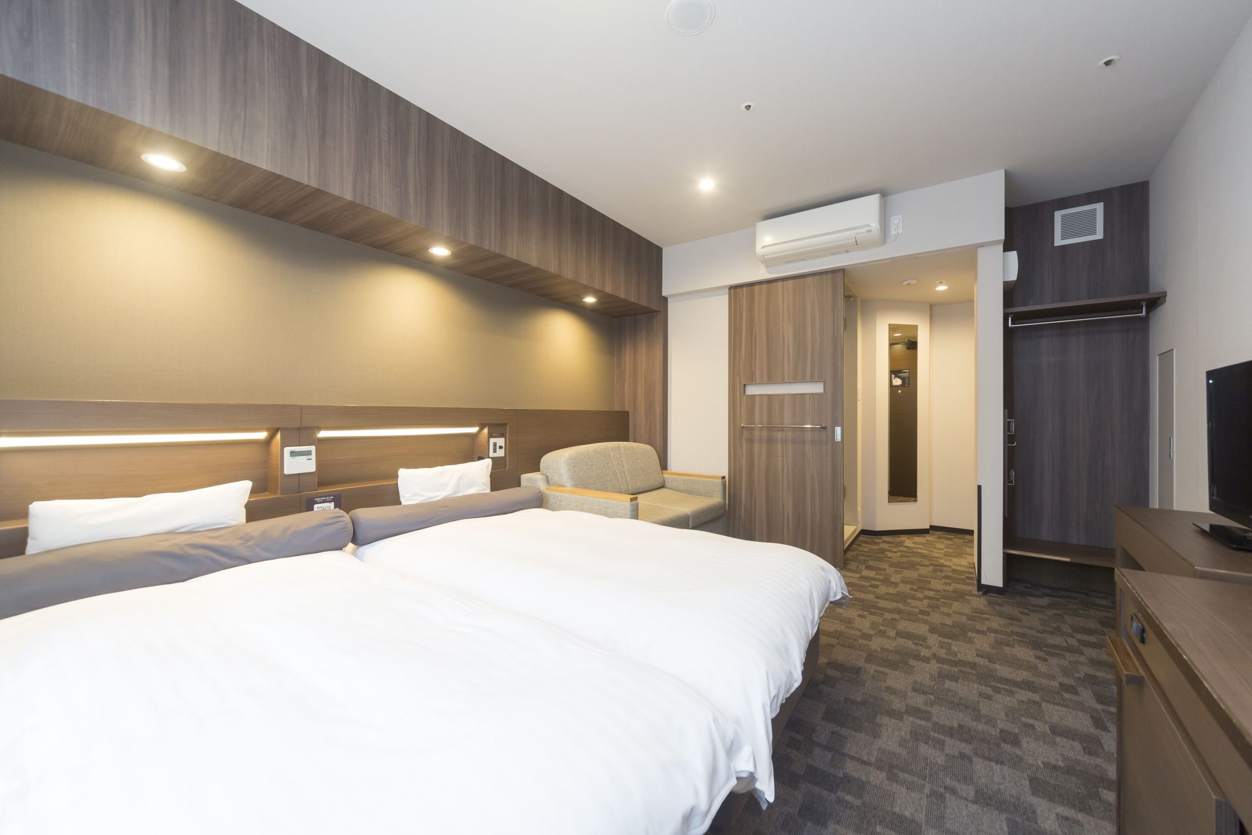 A modern hotel room in Dormy Inn Premium Shibuya, featuring two twin beds, and neutral colors.