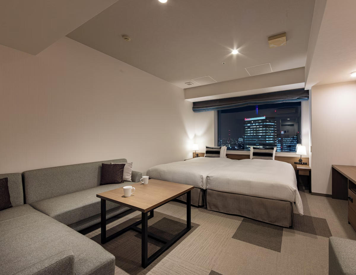 Modern twin room at Tokyu Stay Aoyama with a minimalist design, comfortable sofa, and city views from the window.