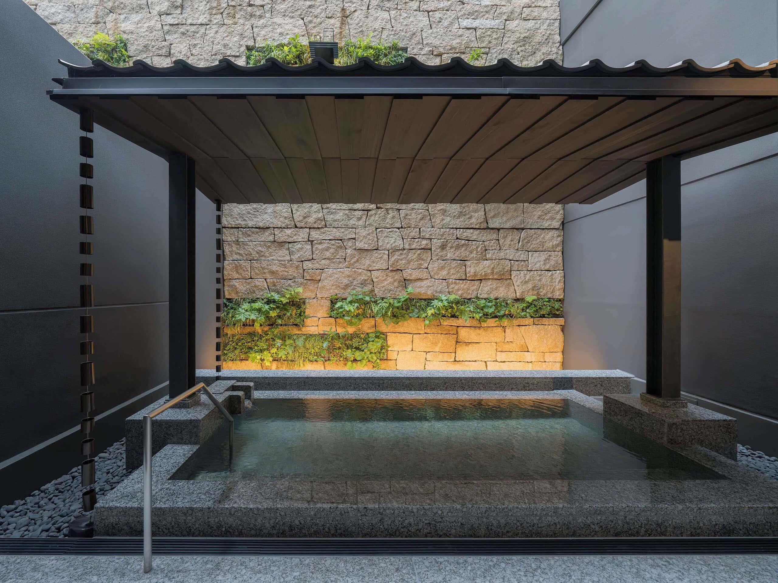 Outdoor onsen bath at Banyan Tree Higashiyama Kyoto surrounded by stone walls and soft lighting, creating a peaceful and private retreat.