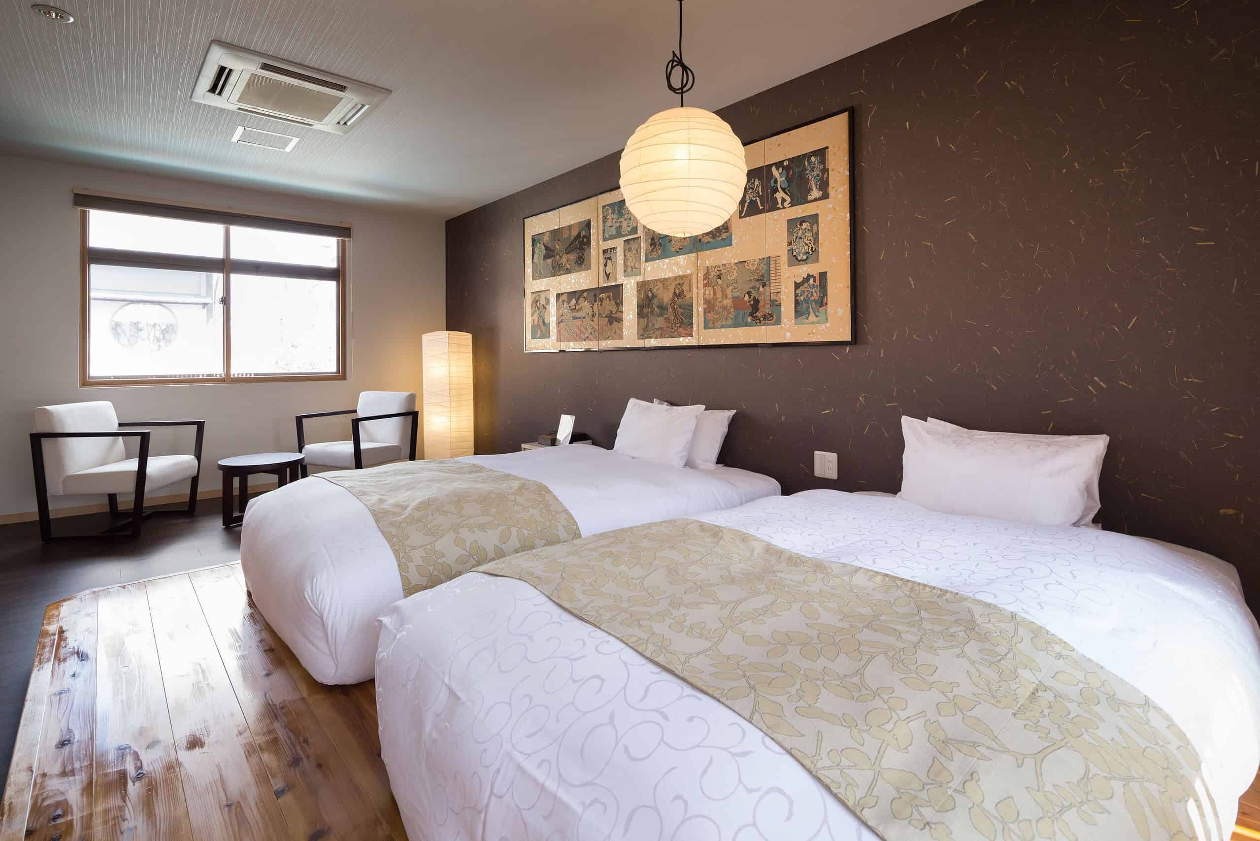 Modern Japanese-style twin room at Nazuna Kyoto Nijo-jo featuring warm lighting, traditional artwork, and contemporary wooden furniture for a relaxing stay.