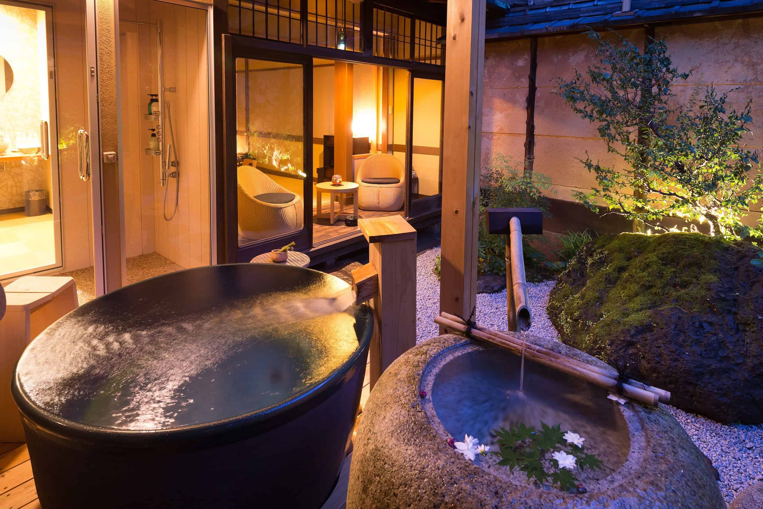 Nazuna Kyoto Nijo-jo offers a romantic evening onsen experience with a softly lit open-air bath overlooking a peaceful Japanese rock garden.