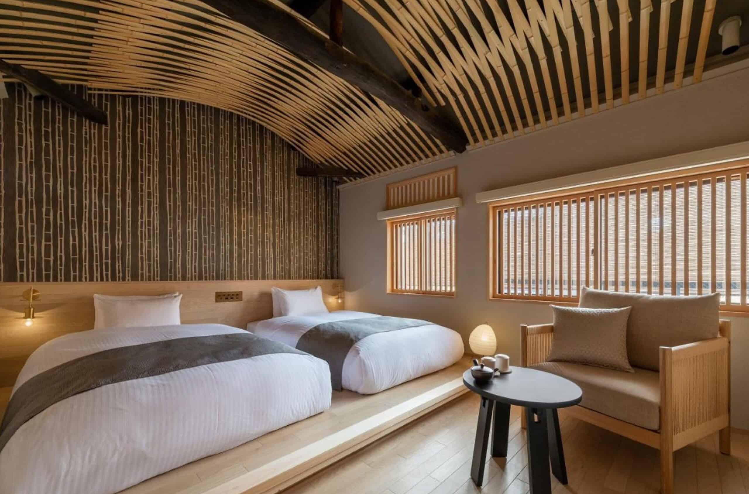 A beautifully designed twin guest room at Nazuna Kyoto Tsubaki St. showcasing modern Japanese interiors, warm lighting, and natural wood craftsmanship.