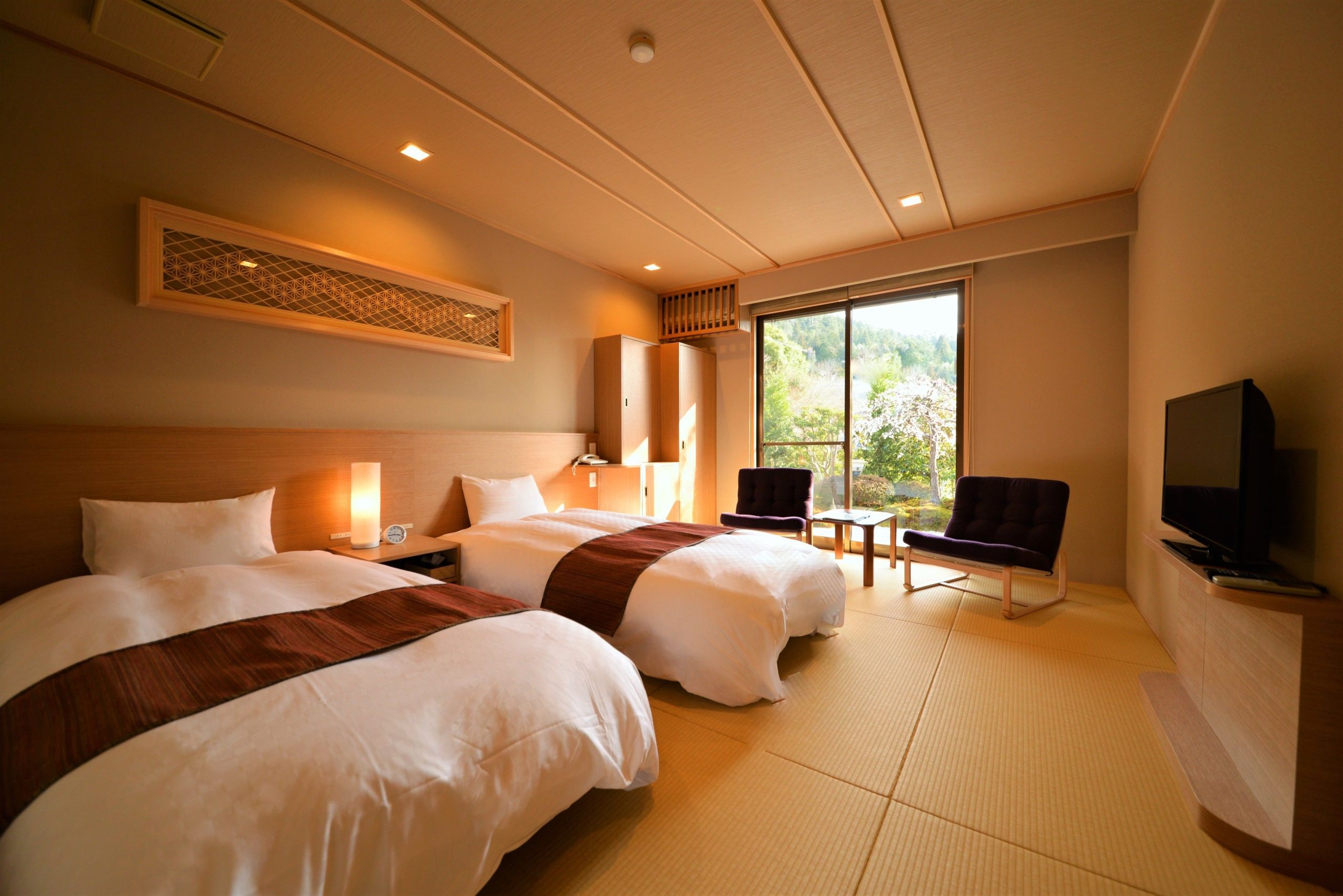 Tatami-style room at Seryo Ryokan with twin beds, minimalist decor, and a large window framing a peaceful garden view.