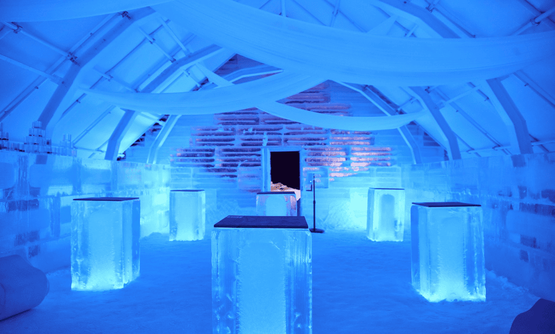An icy blue interior of Geimori ice bar in Sapporo with glowing ice tables, frosty walls, and soft white drapery hanging from the ceiling.