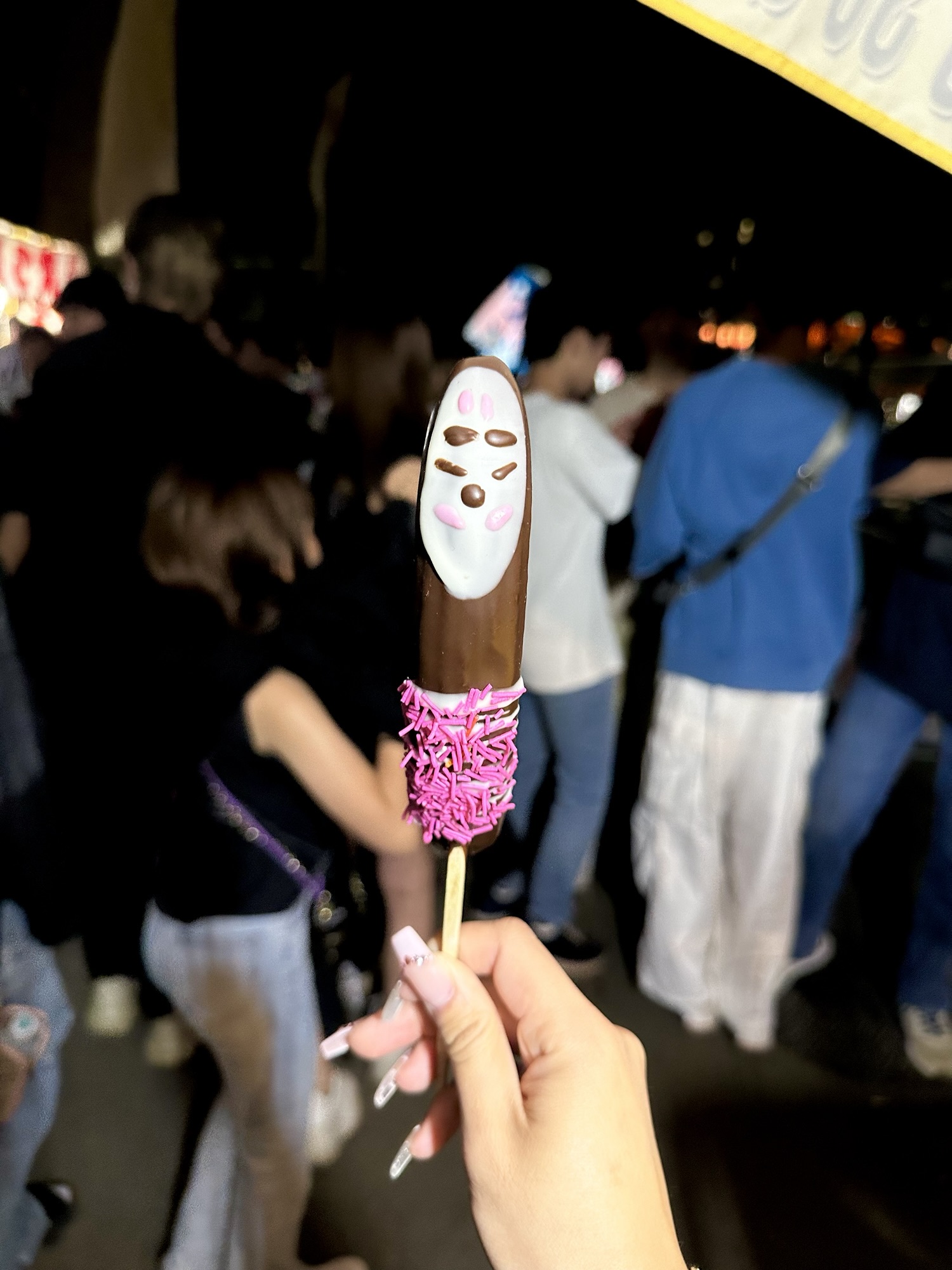 A chocolate banana with pink sprinkles, a popular street stall snack during Kurayami Matsuri Darkness Festival in Tokyo